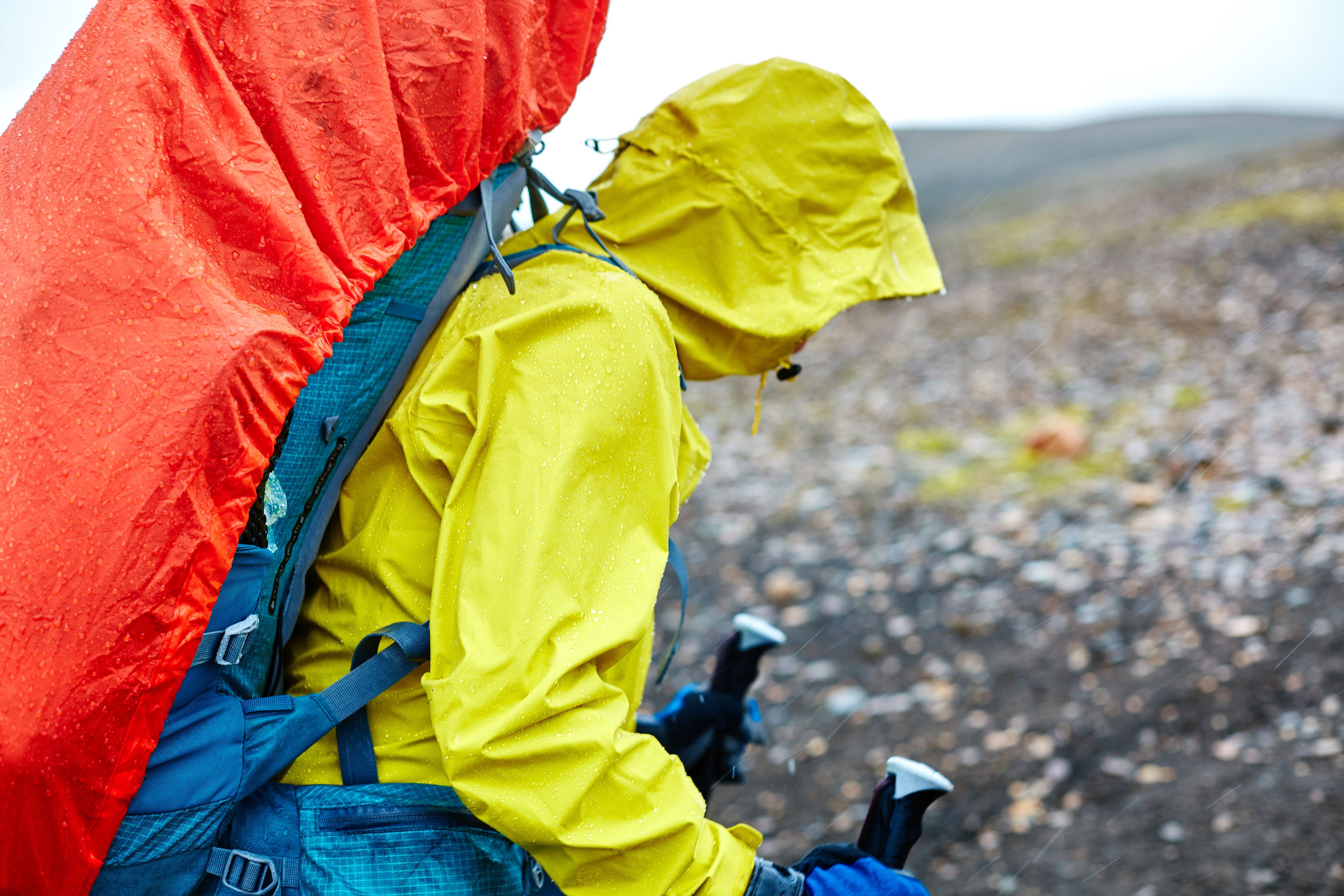 woman walking in the rain with a backpack in a raincoat and wearing a waterproof jacket, Iceland