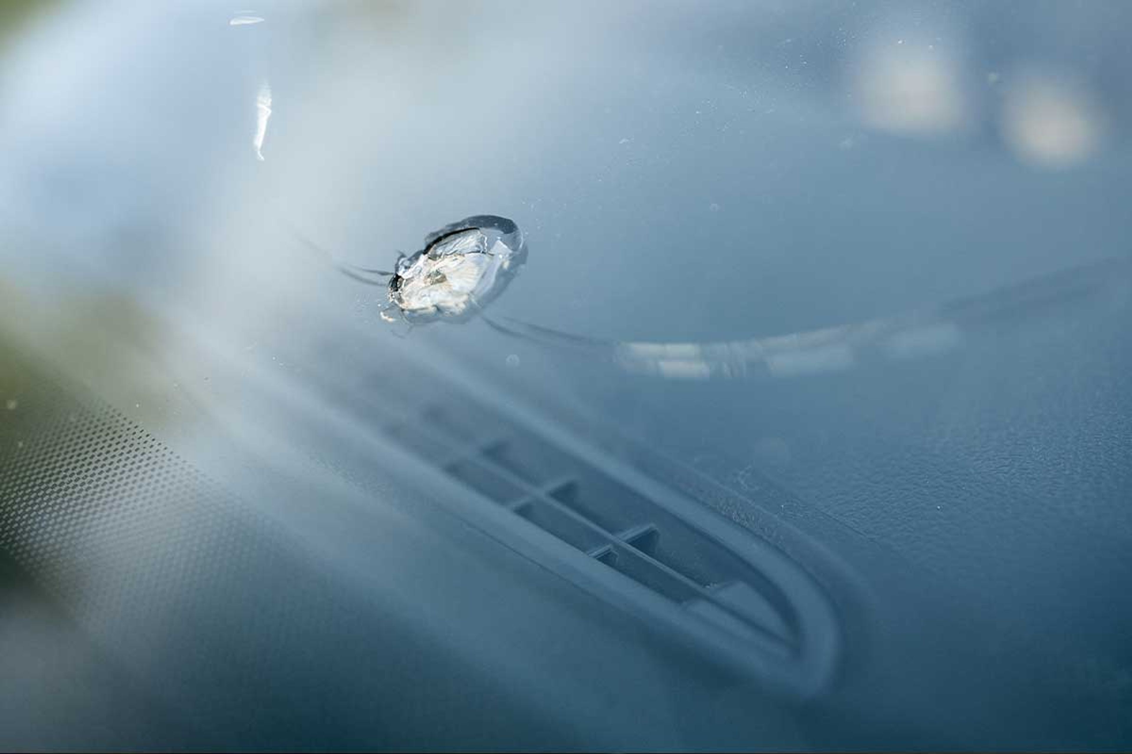 Broken windshield with cracks and shattered glass on a car parked on the side of the road in Iceland