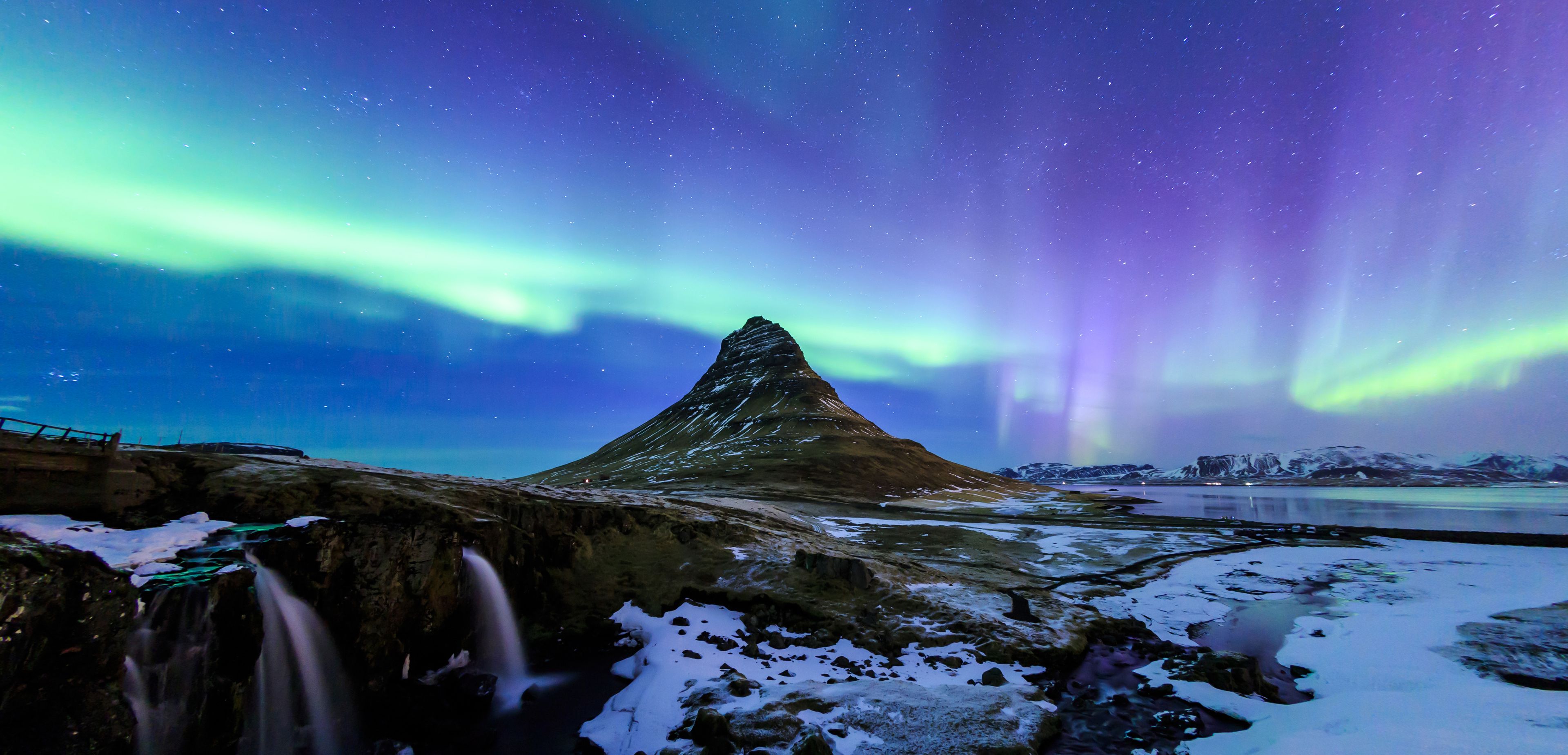magnificent view of the green and purple aurora borealis offered by the snowy landscape and the Kirkjufell mountain 