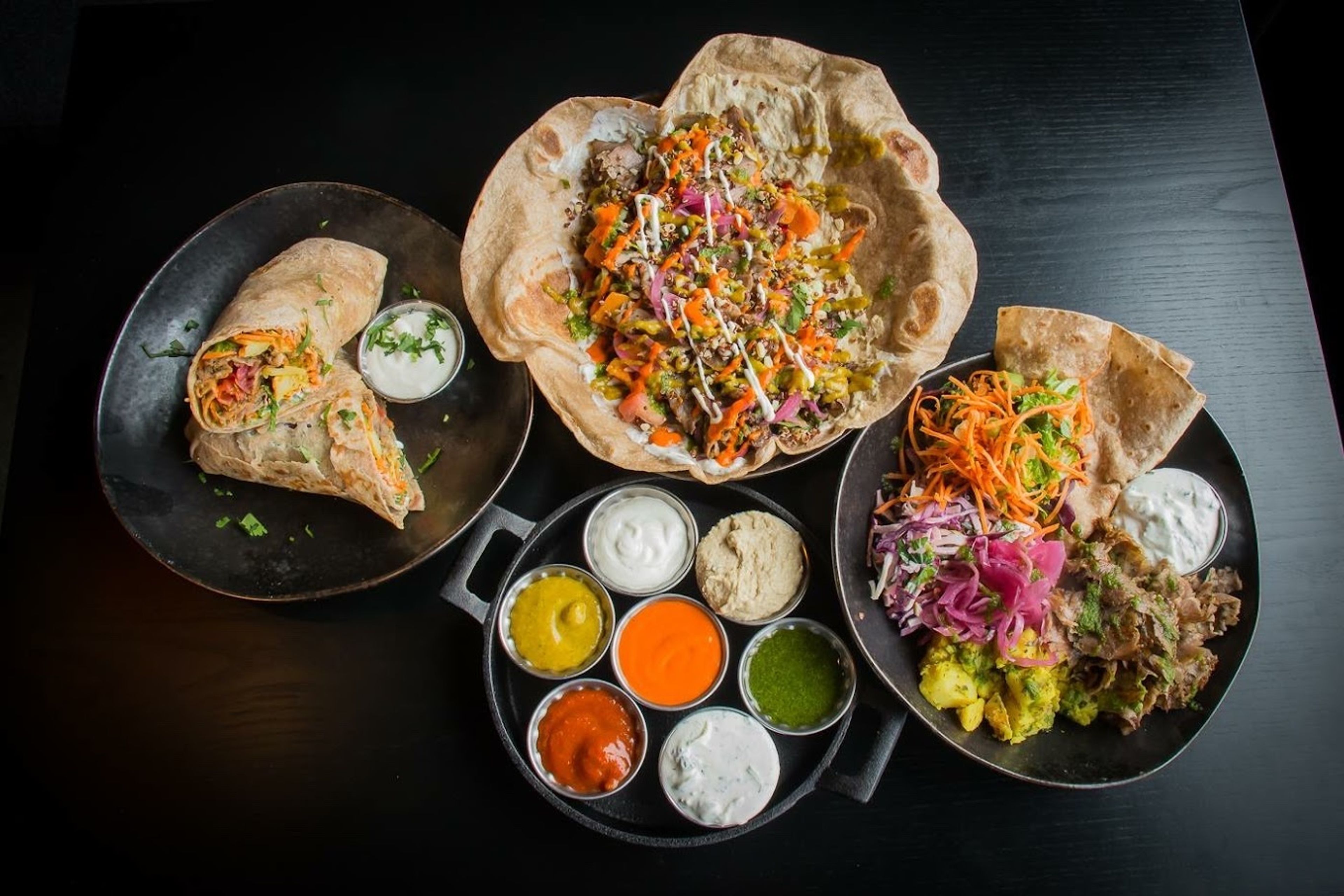 3 dishes and a tray of colorful sauces at Lamb Street Food, Iceland 