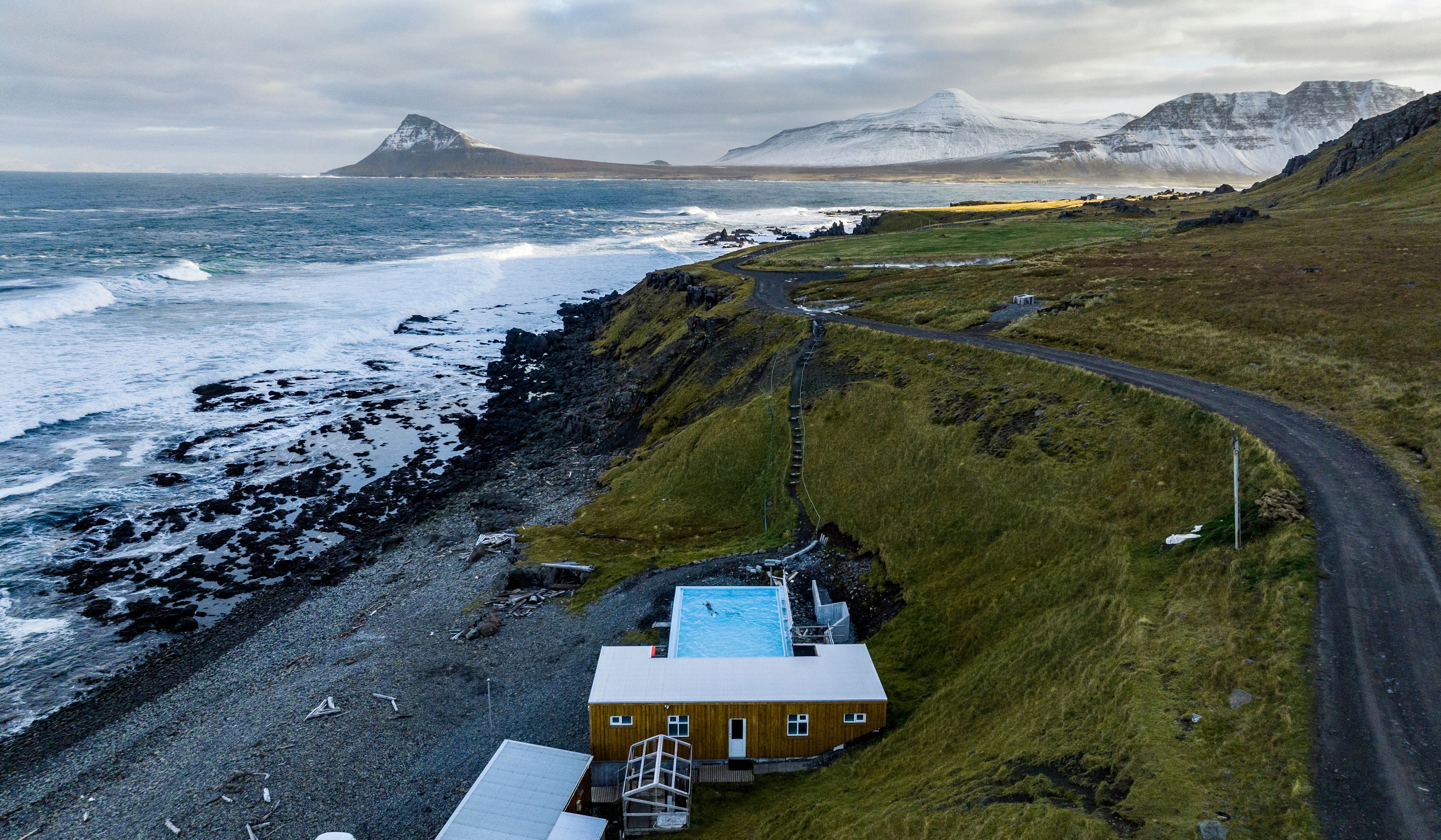 Krossneslaug Hot Spring, Iceland aerial view of a well maintained krossneslaug pool a natural hot springs with fjords in the background in mid may
