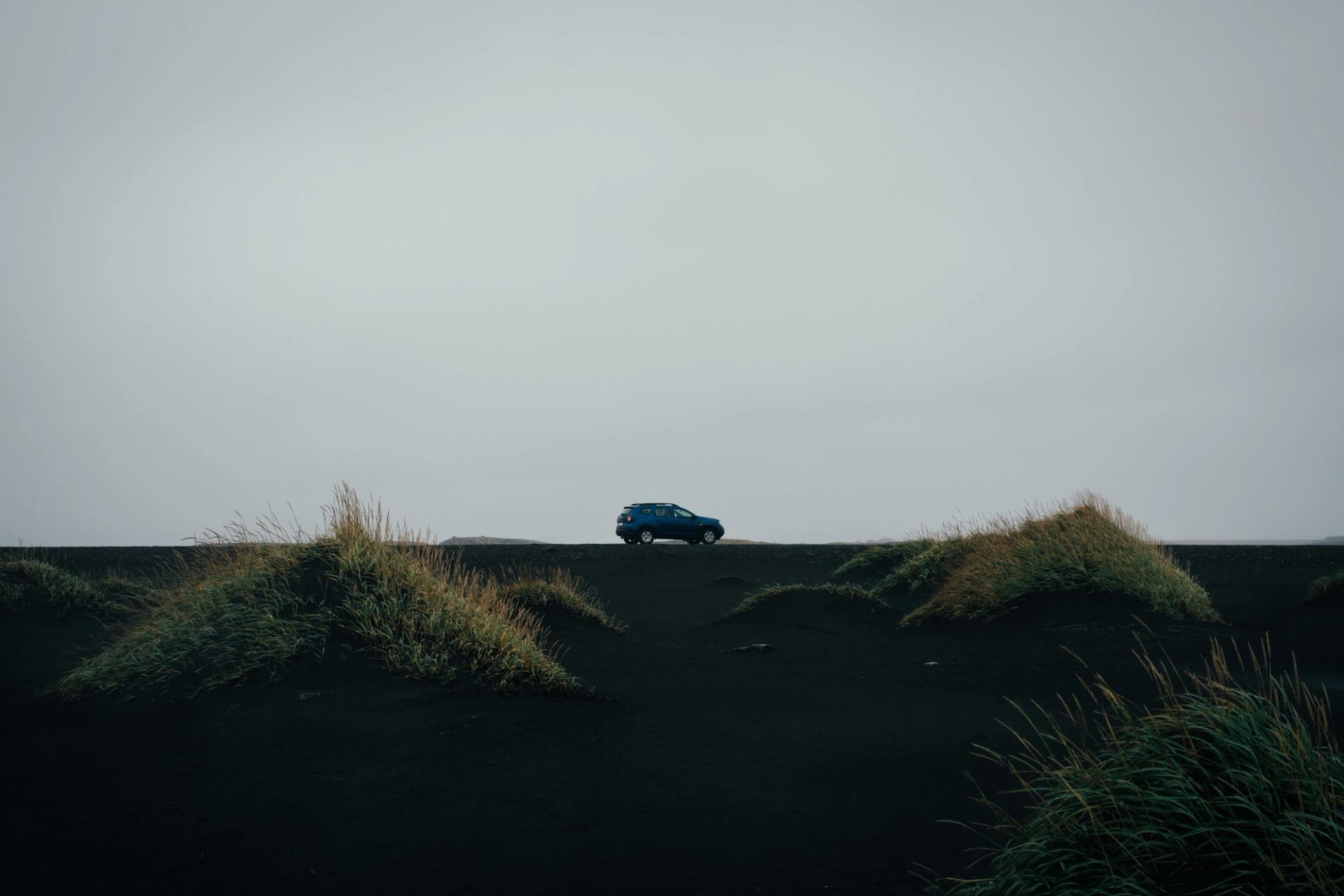 a blue rental car in the landscapes of Iceland