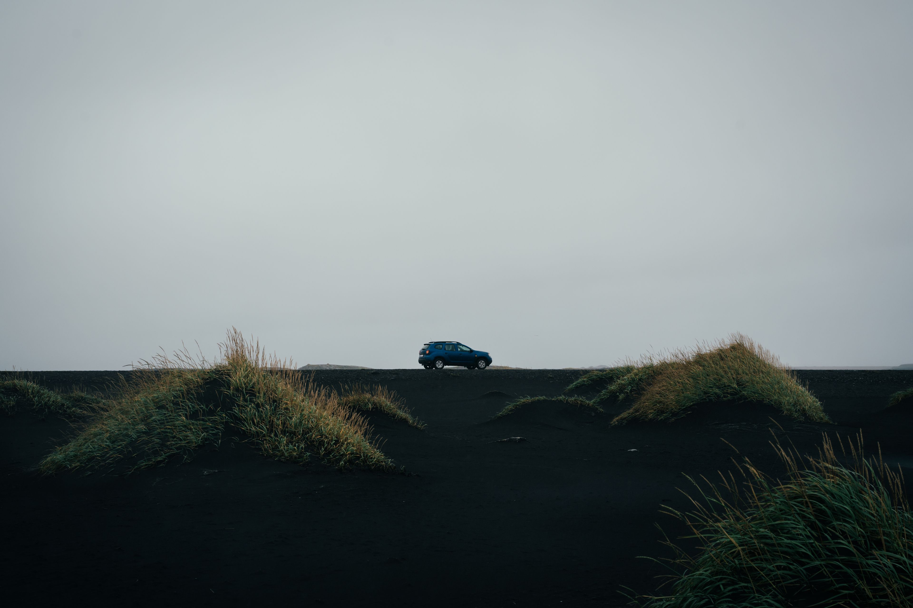 a blue rental car in the landscapes of Iceland