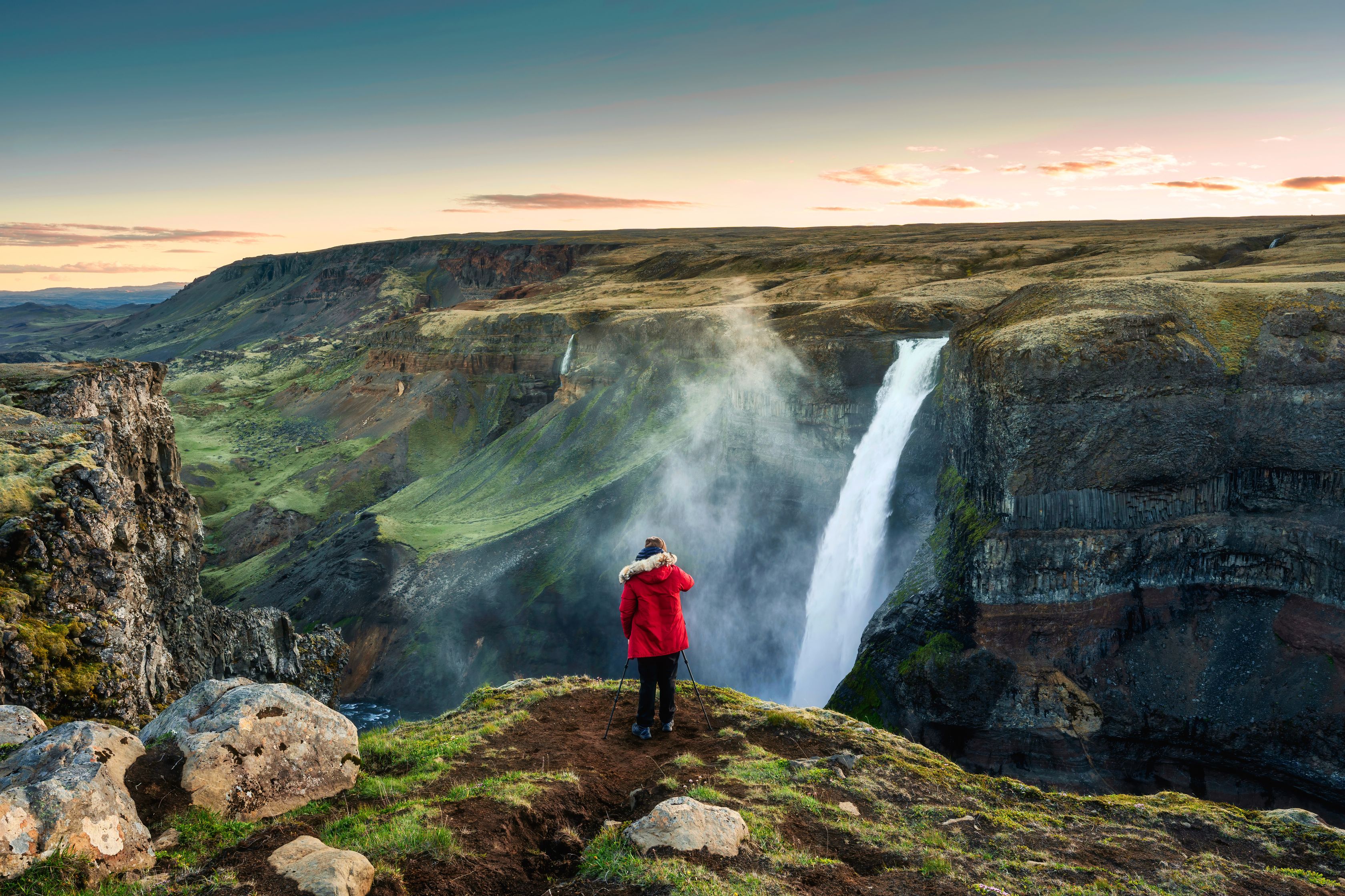 Girl in a red jacket admiring Haifoss from a viewpoint