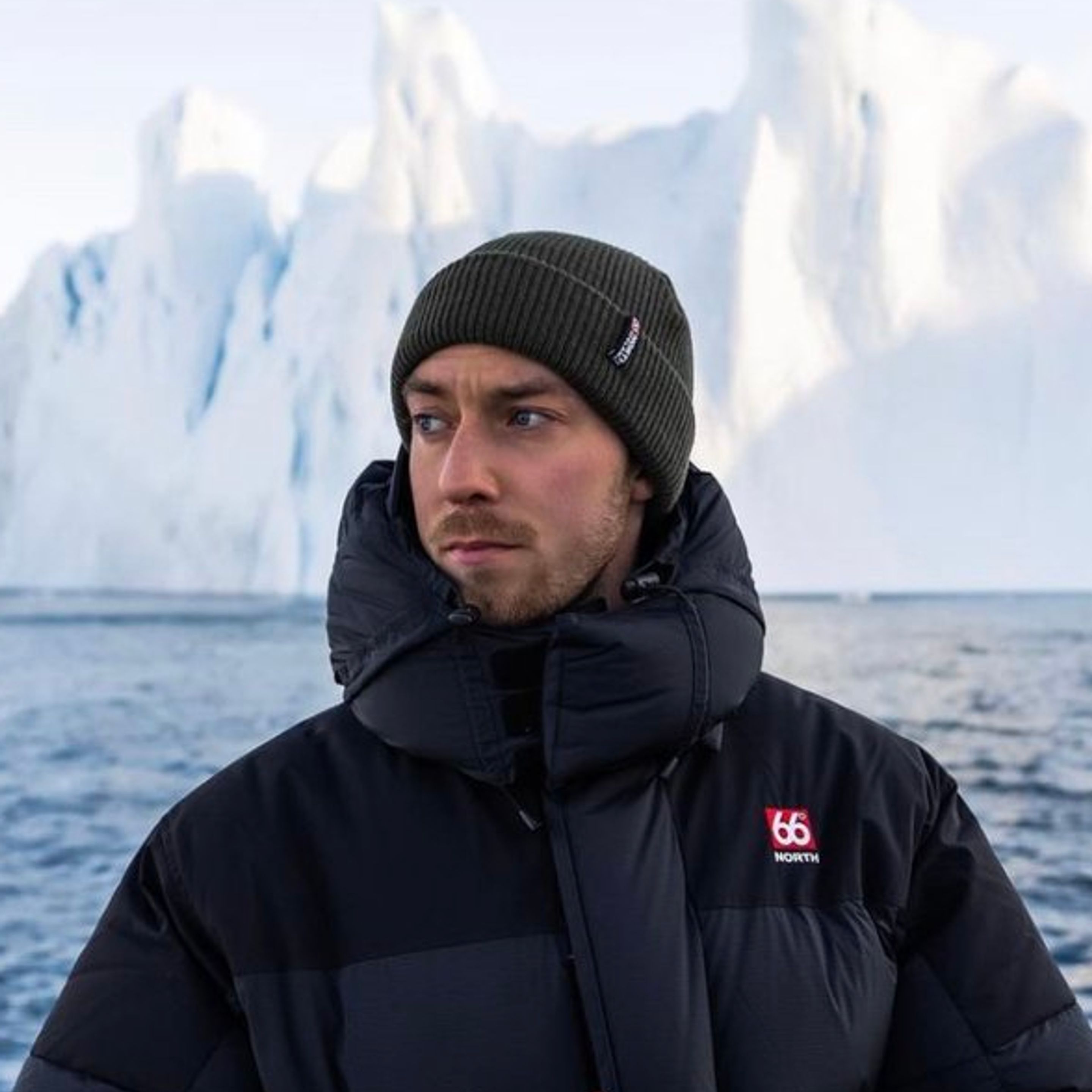 Jón from Iceland tenant son appareil photo près d’une eau bleue et des montagnes de glace autour de l’Islande