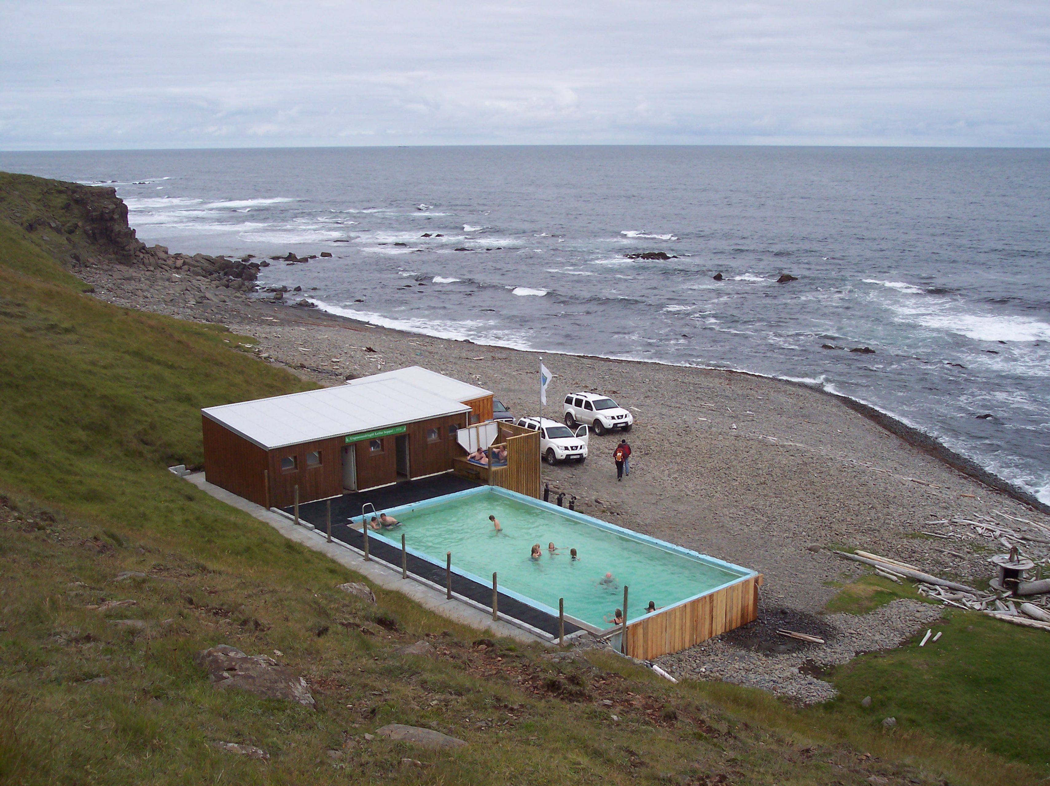 a view from above of Krossneslaug hot spring in iceland, showing changing rooms with showers for the geothermal pool