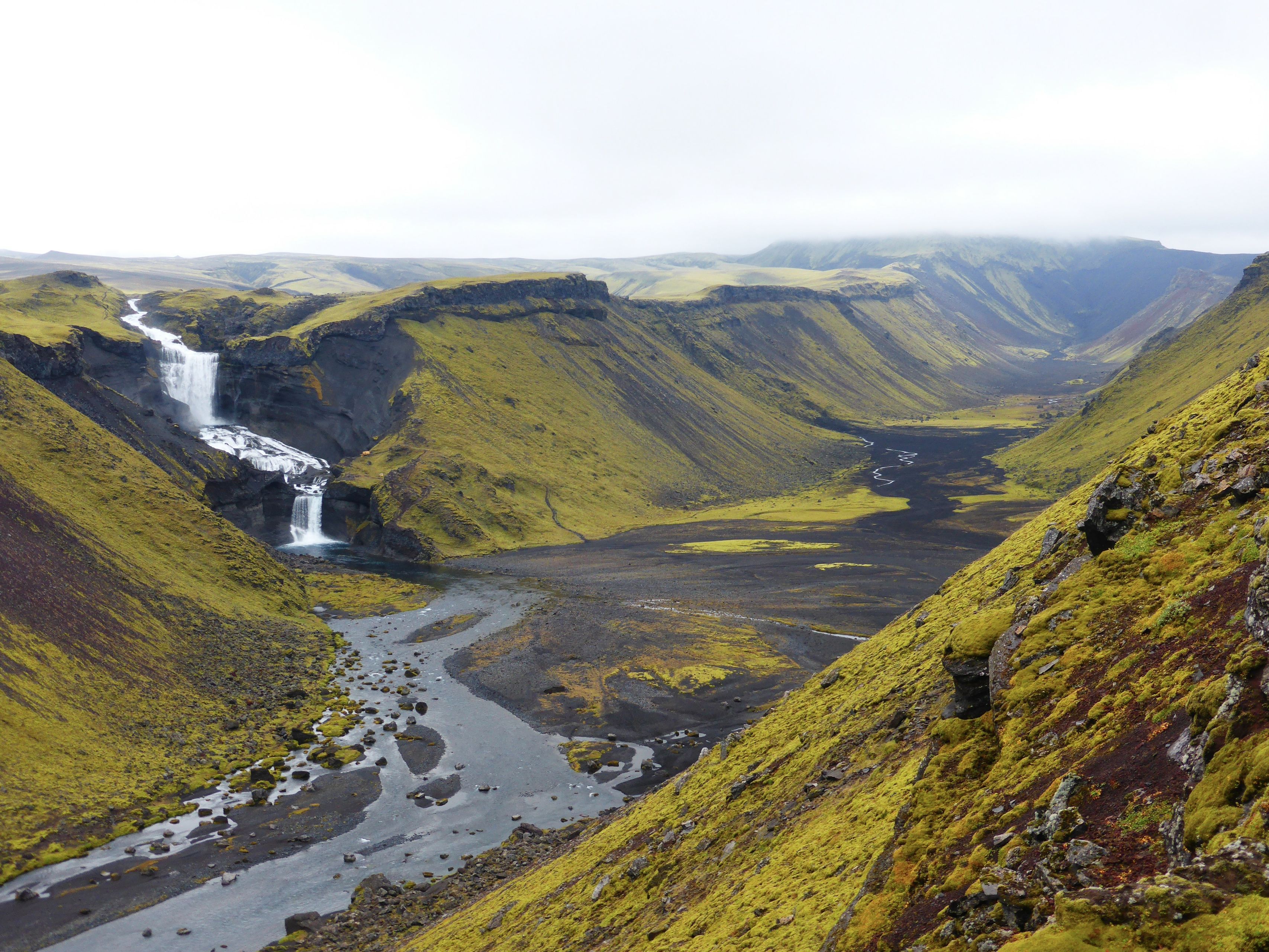 Valley at Eldgjá, Iceland. Green vegetation, blue river, and a waterfall.