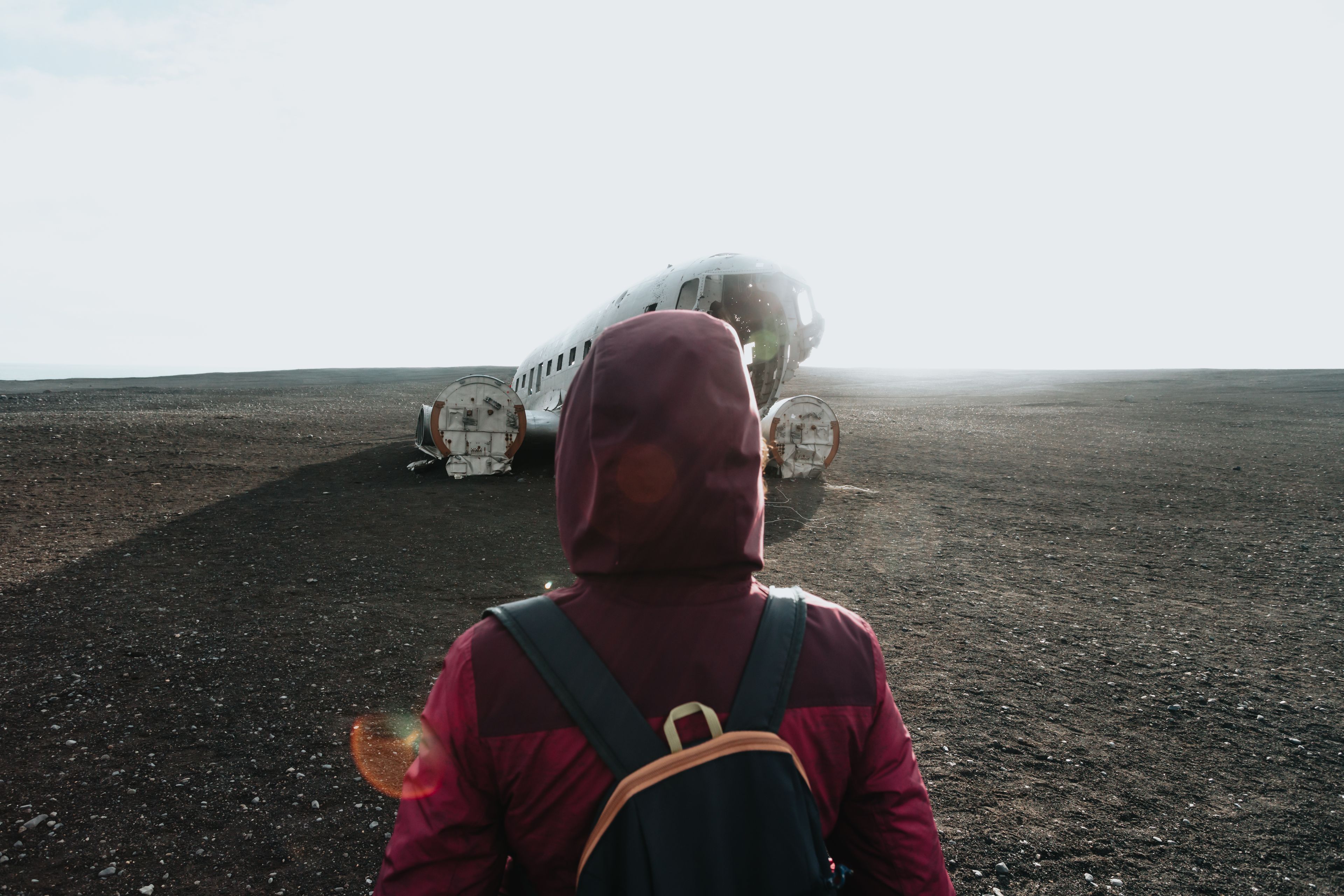 Woman in winter clothes in front of the wreck of the crashed airplane in Iceland