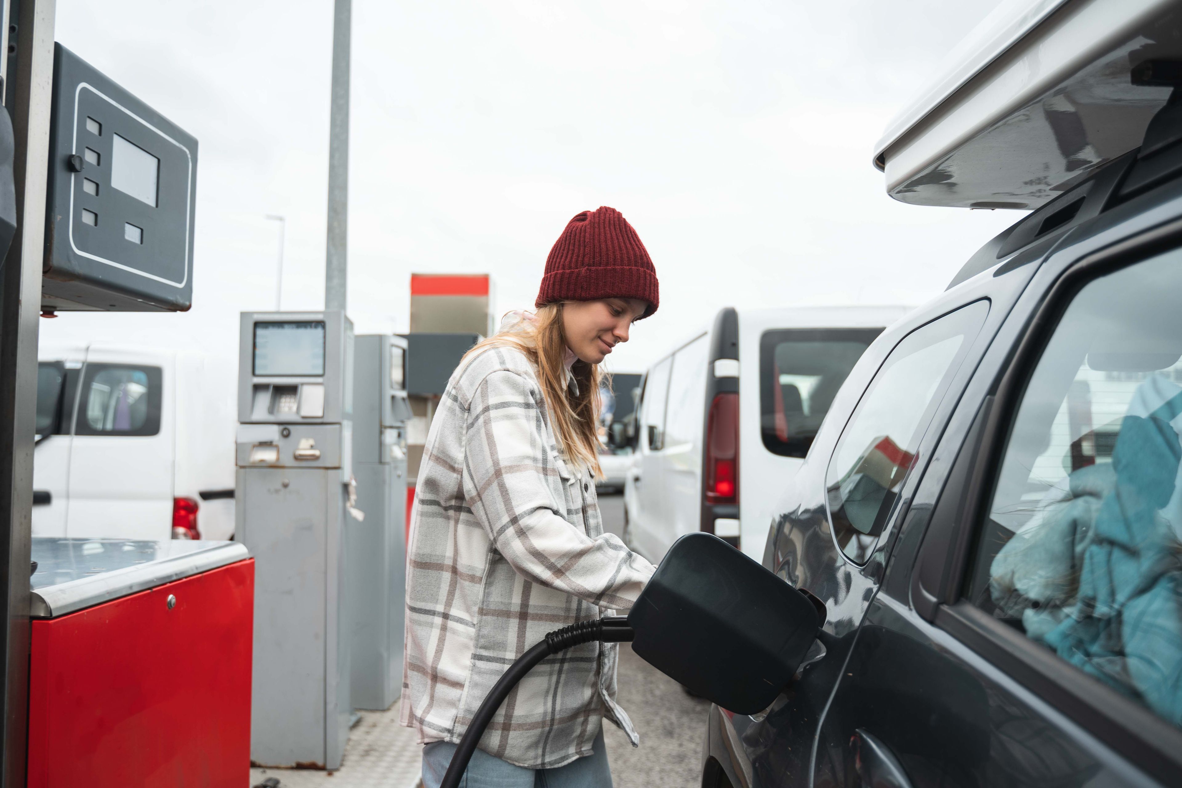 Woman refilling a rental car with fuel at the gas station in iceland