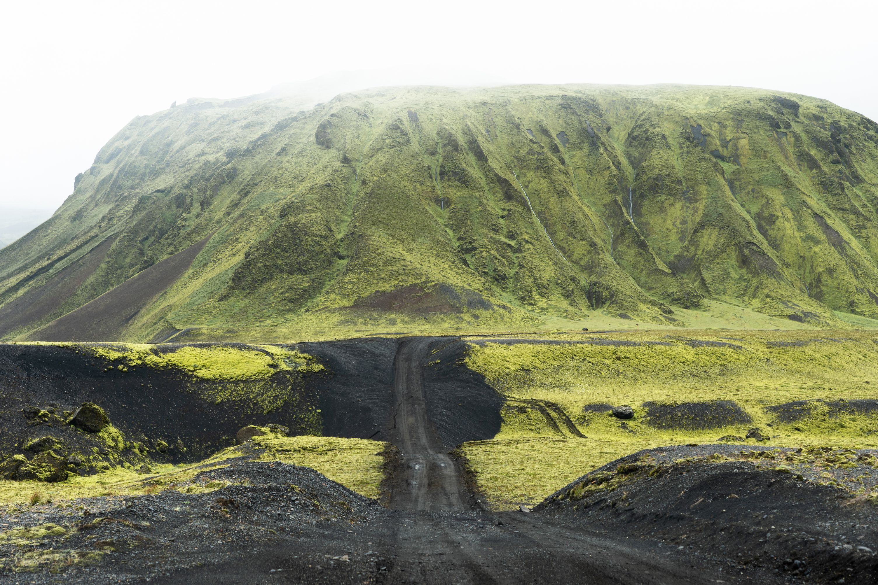 Black gravel highland F-Roads In Iceland with green mountain in the background