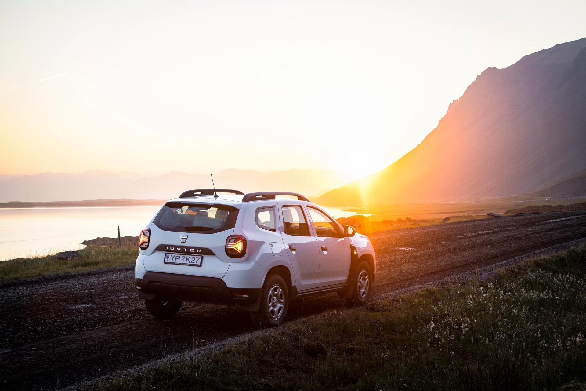 White 4x4 Dacia Duster rental car parked in Iceland while watching the sunset
