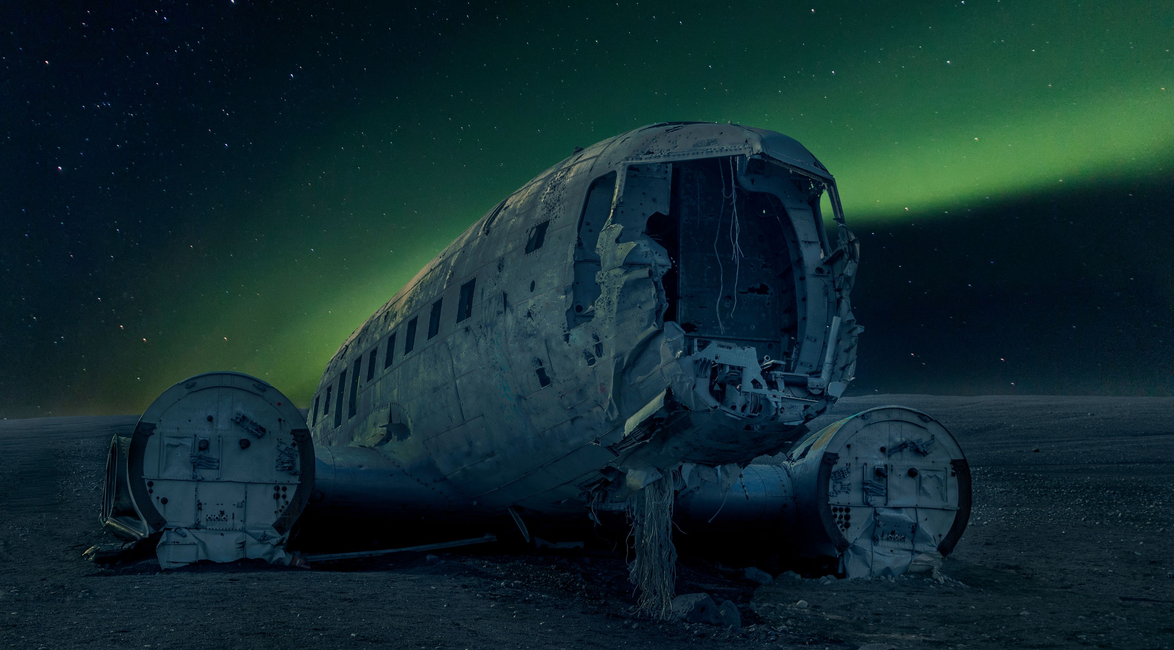view on the famous DC plane abandoned in Iceland, and magnificent northern lights in a clear, blue and starry sky 