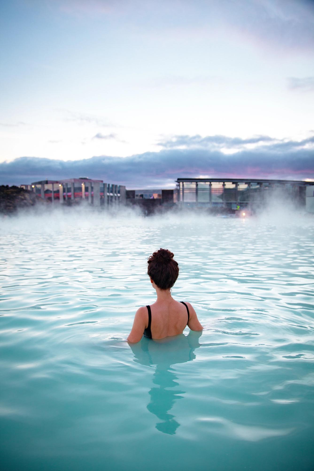 A woman relaxing in a geothermal pool also known as hot springs in iceland that has warm water with perfect temperature