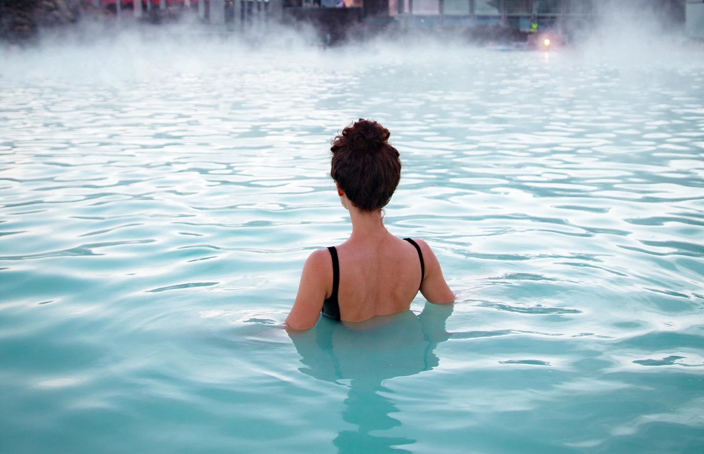 A woman relaxing in a geothermal pool also known as hot springs in iceland that has warm water with perfect temperature