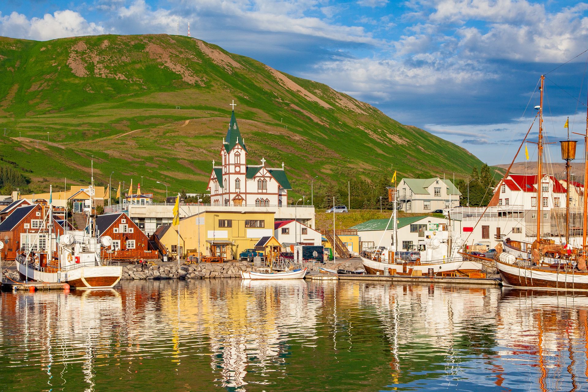 view on the city of Husavik, its port and its moored boats, blue summer sky 
