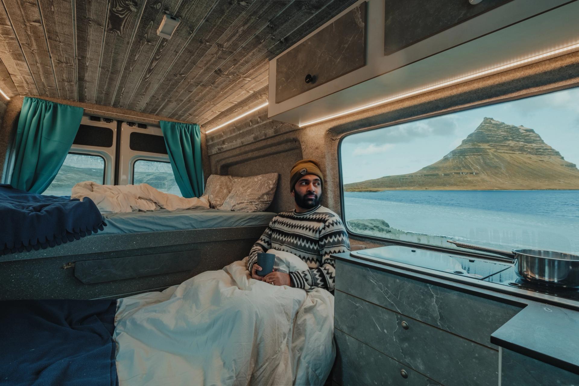 A person realxing inside his campervan  on a small parking lot near mt kirkjufell
