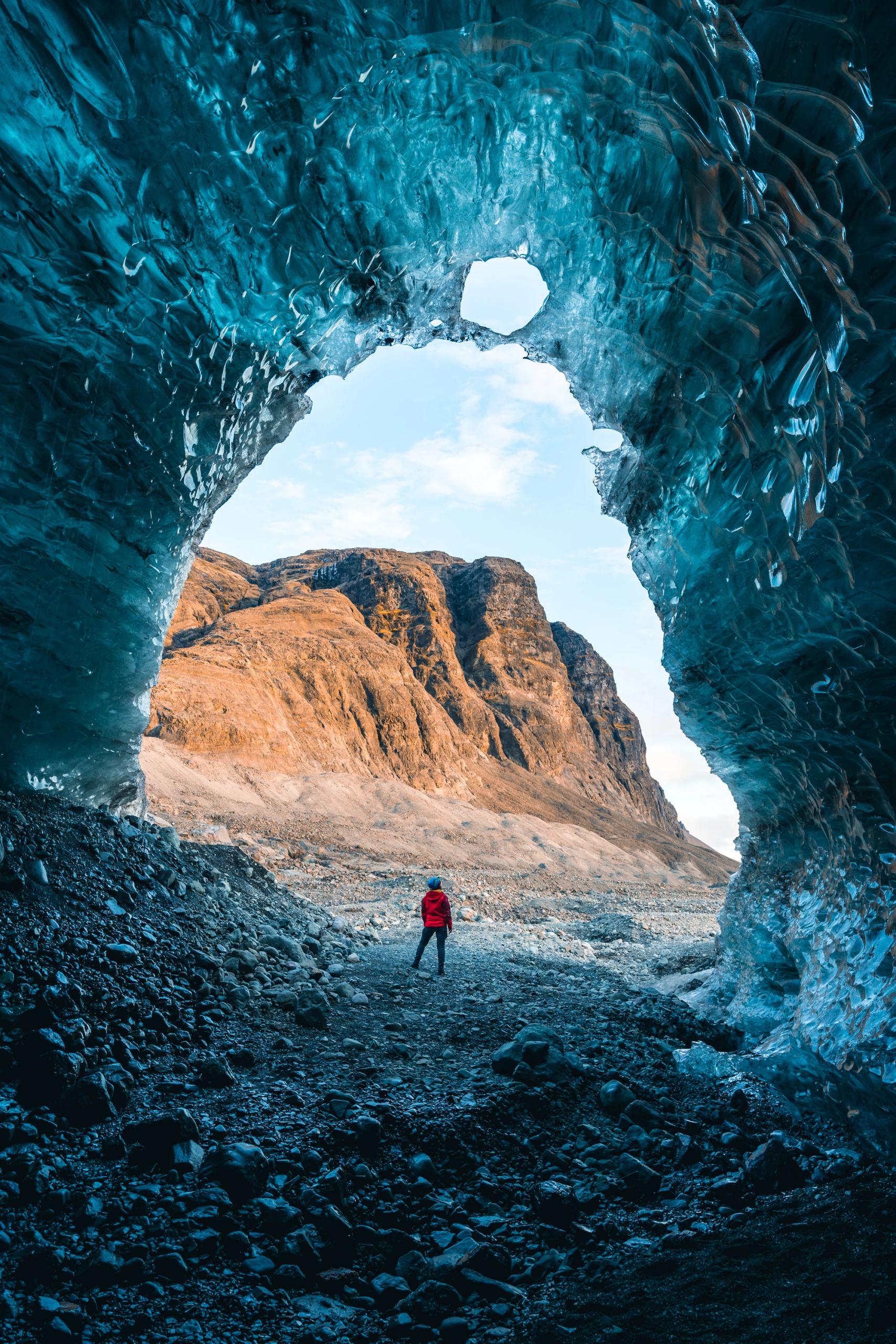 Person standing by the entrance of an ice cave