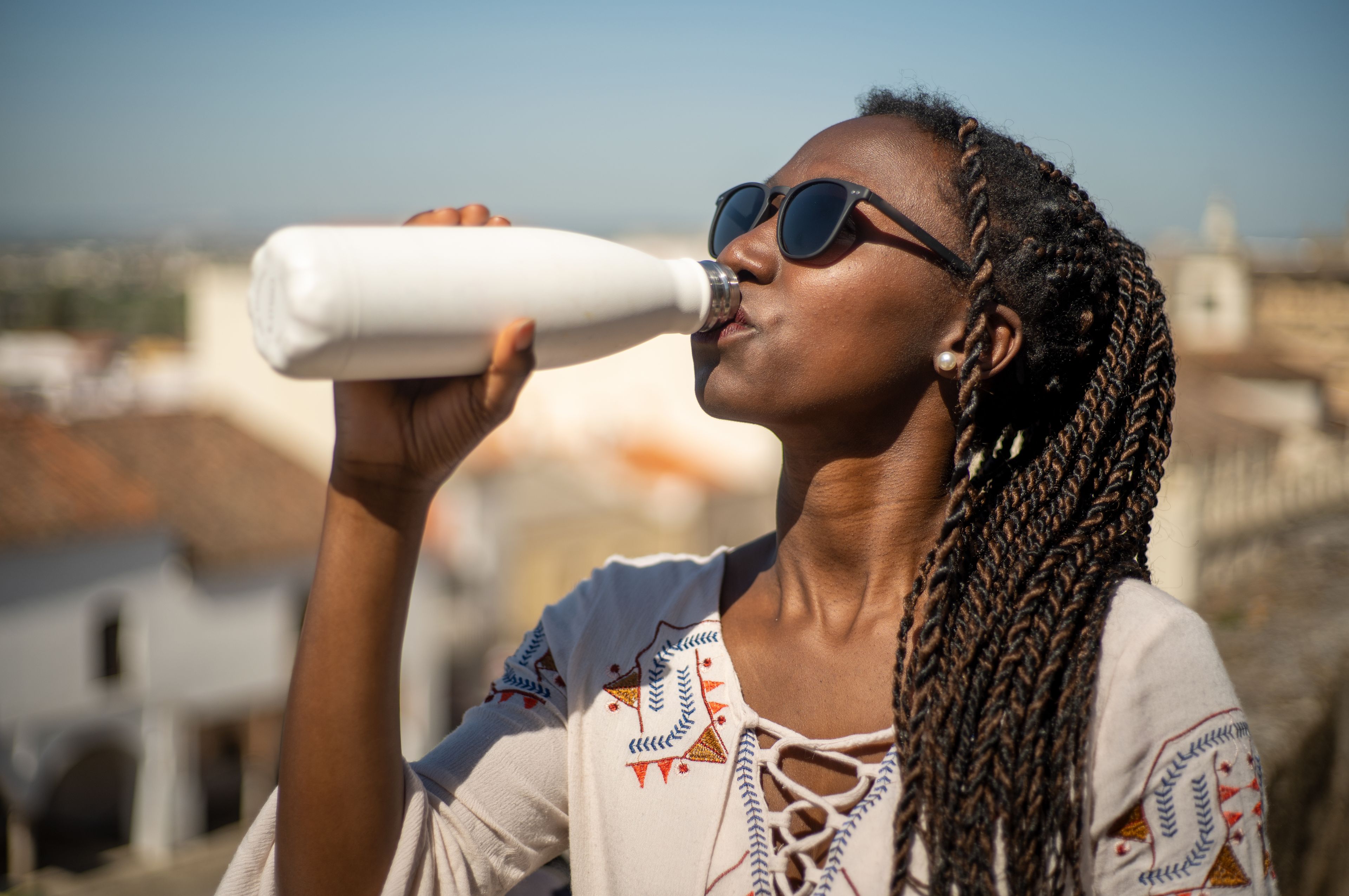 Chica bebiendo agua de una botella reusable