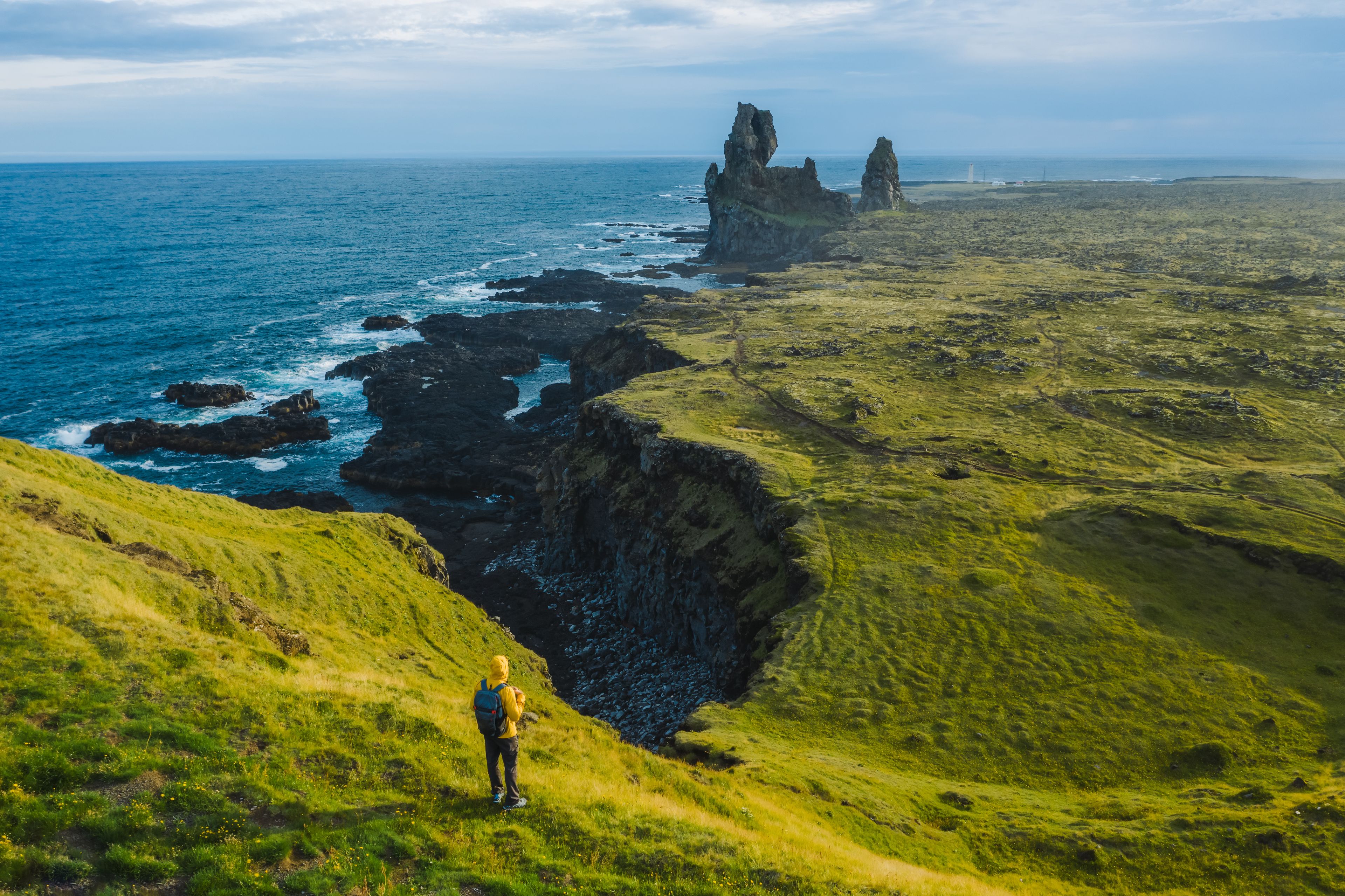 Man in yellow jacket standing in front of Lóndrangar Basalt Cliffs in Iceland