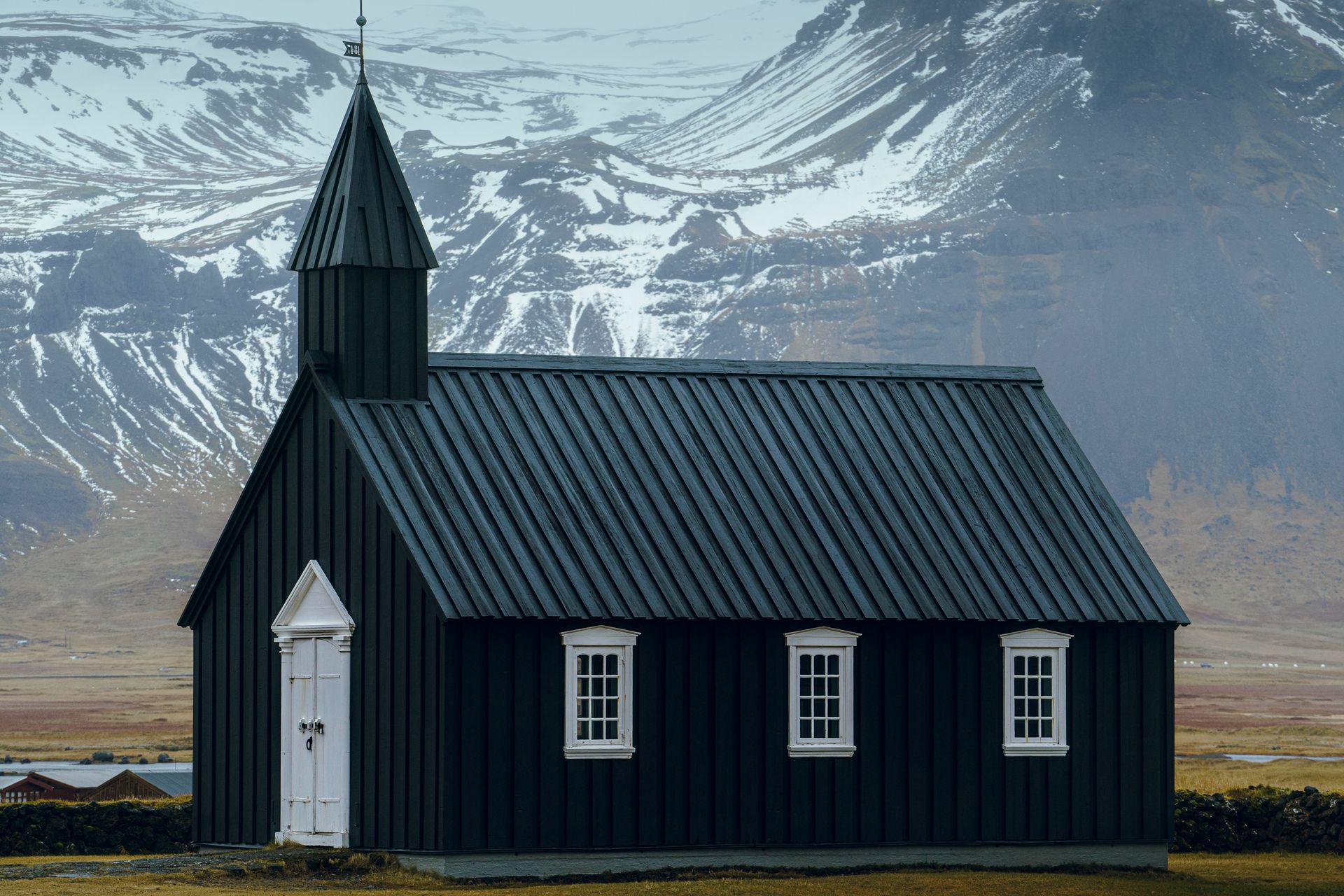 View on the Budir black church and the snowy mountains in the background  