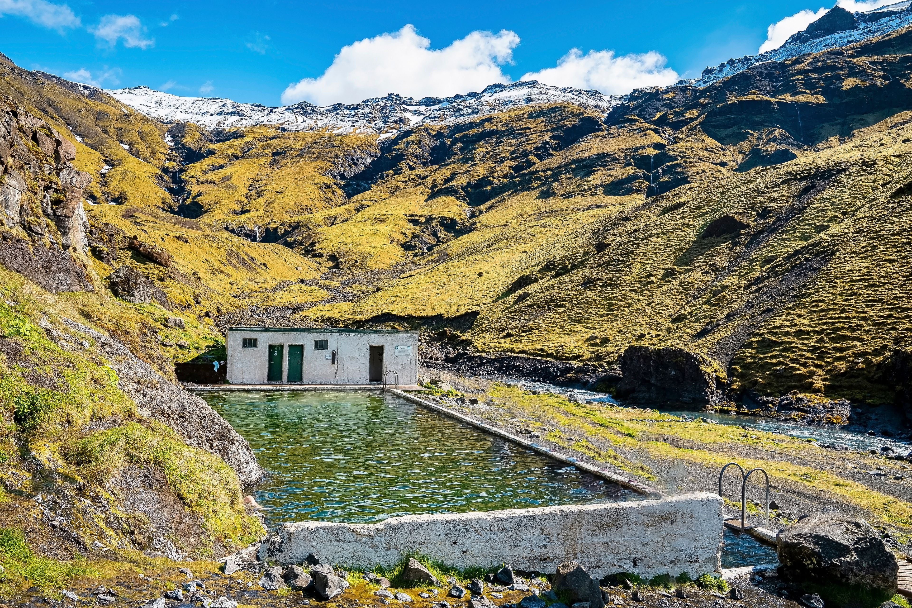 Visit iceland and dive into this natural geothermal pool that is naturally heated in the middle of mountains in Iceland