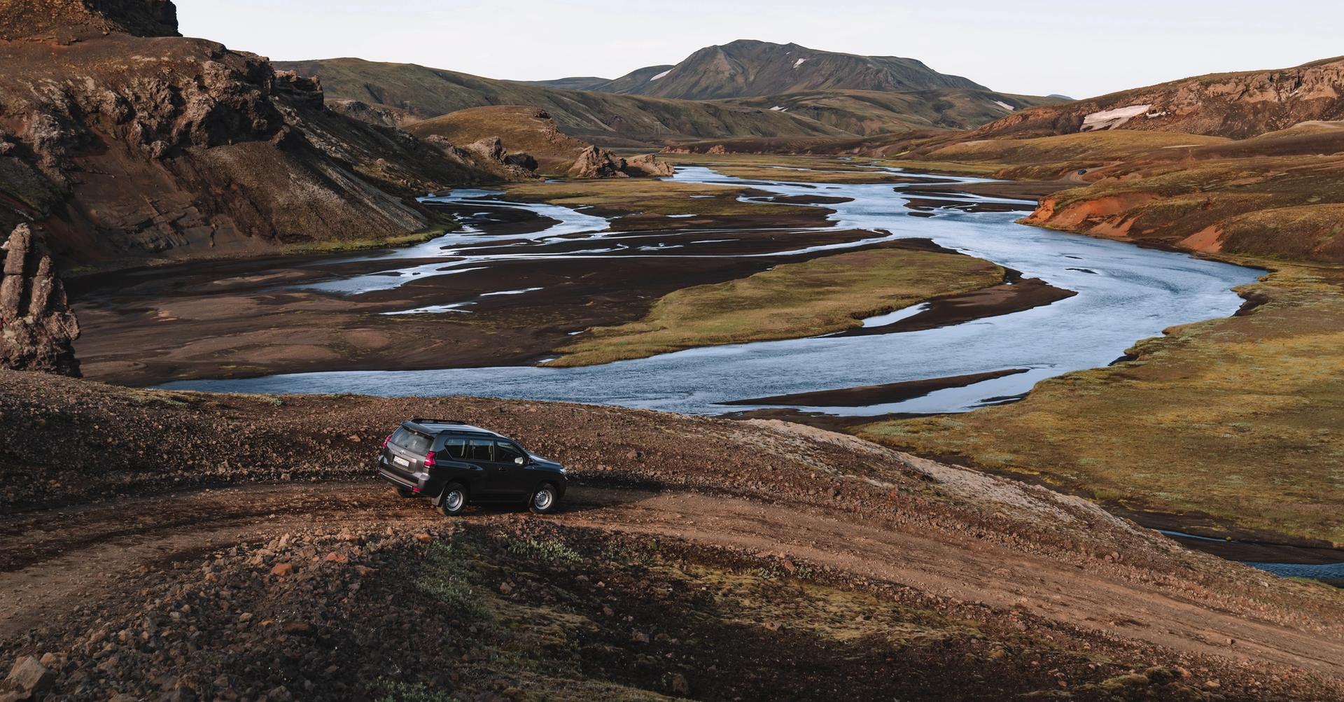 A Toyota Land Cruiser from Go Car Rental parked in Iceland with a captivating landscape backdrop featuring black sand beaches and the country's unique tectonic plates.