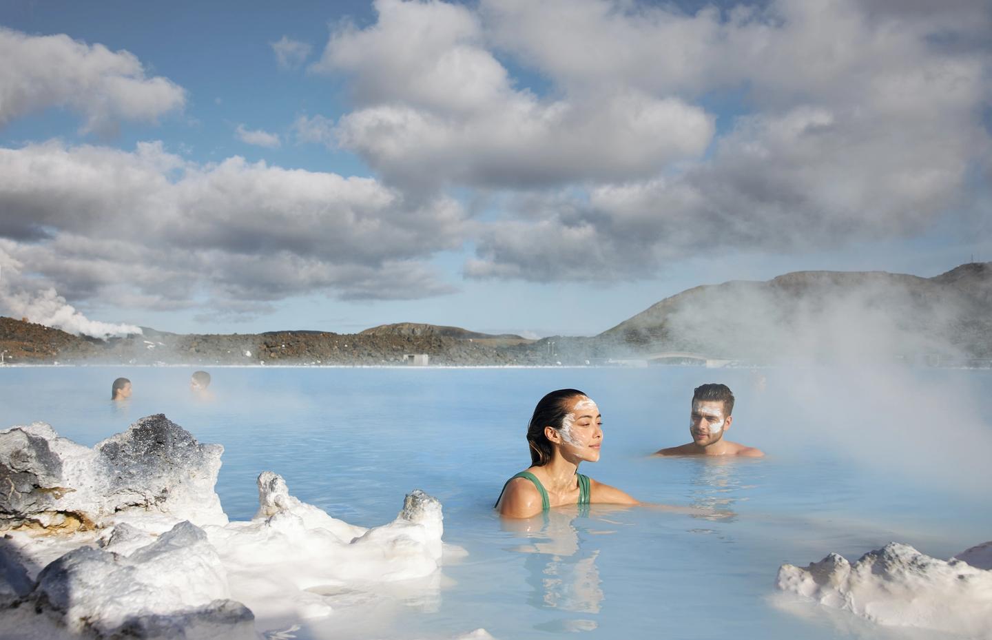 Man and a woman with a face max in blue lagoon hot spring in Iceland