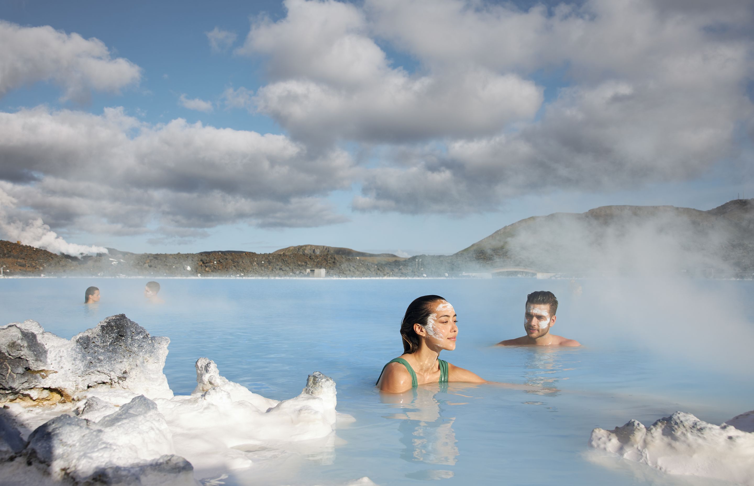 Man and a woman with a face max in blue lagoon hot spring in Iceland