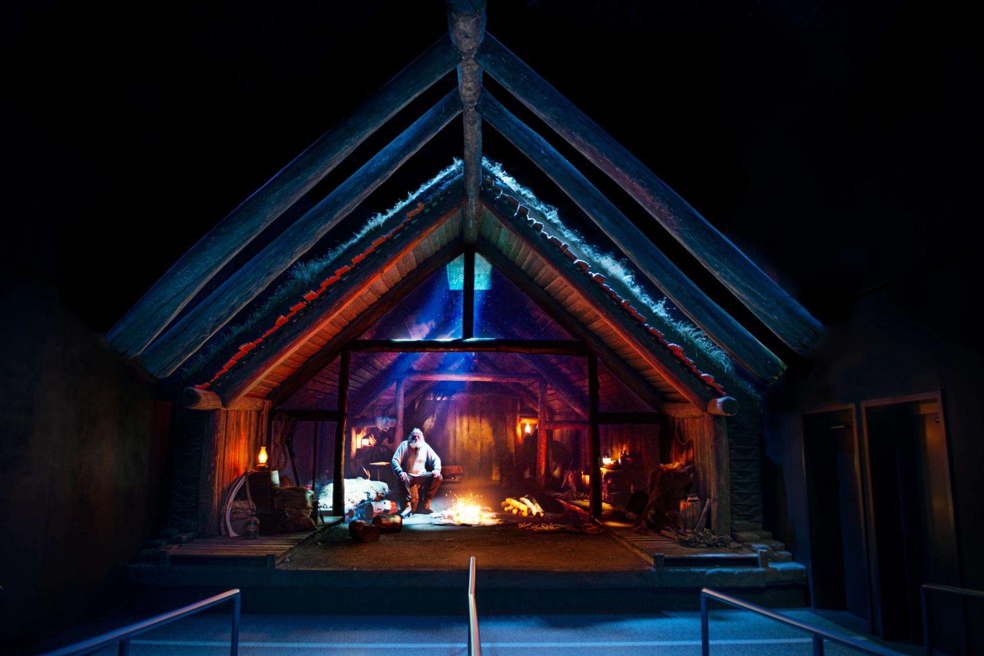 A man standing in an icelandic turf house in the entry to fly over iceland