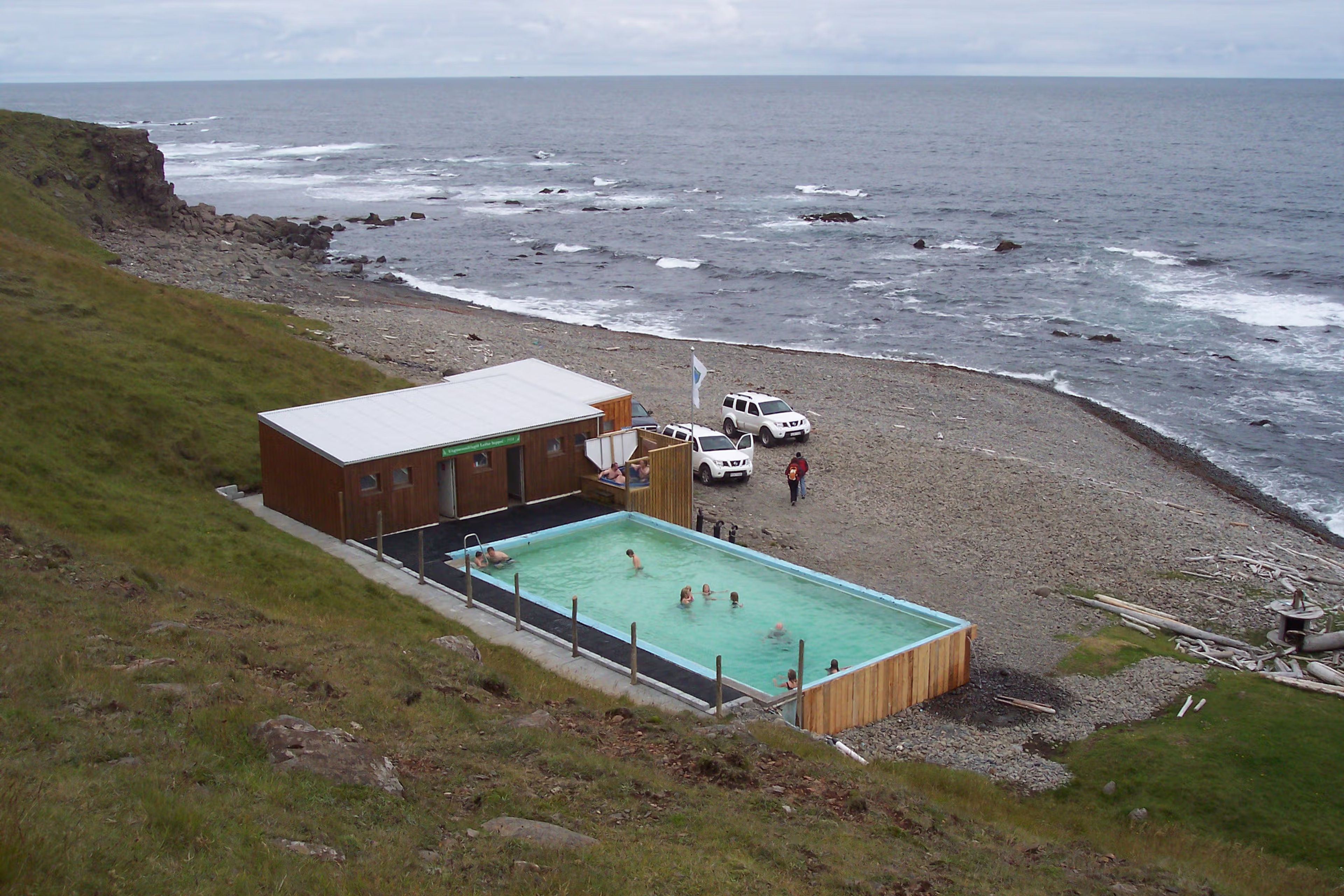 Piscinas naturales de Krossneslaug con gente dentro y el mar de fondo