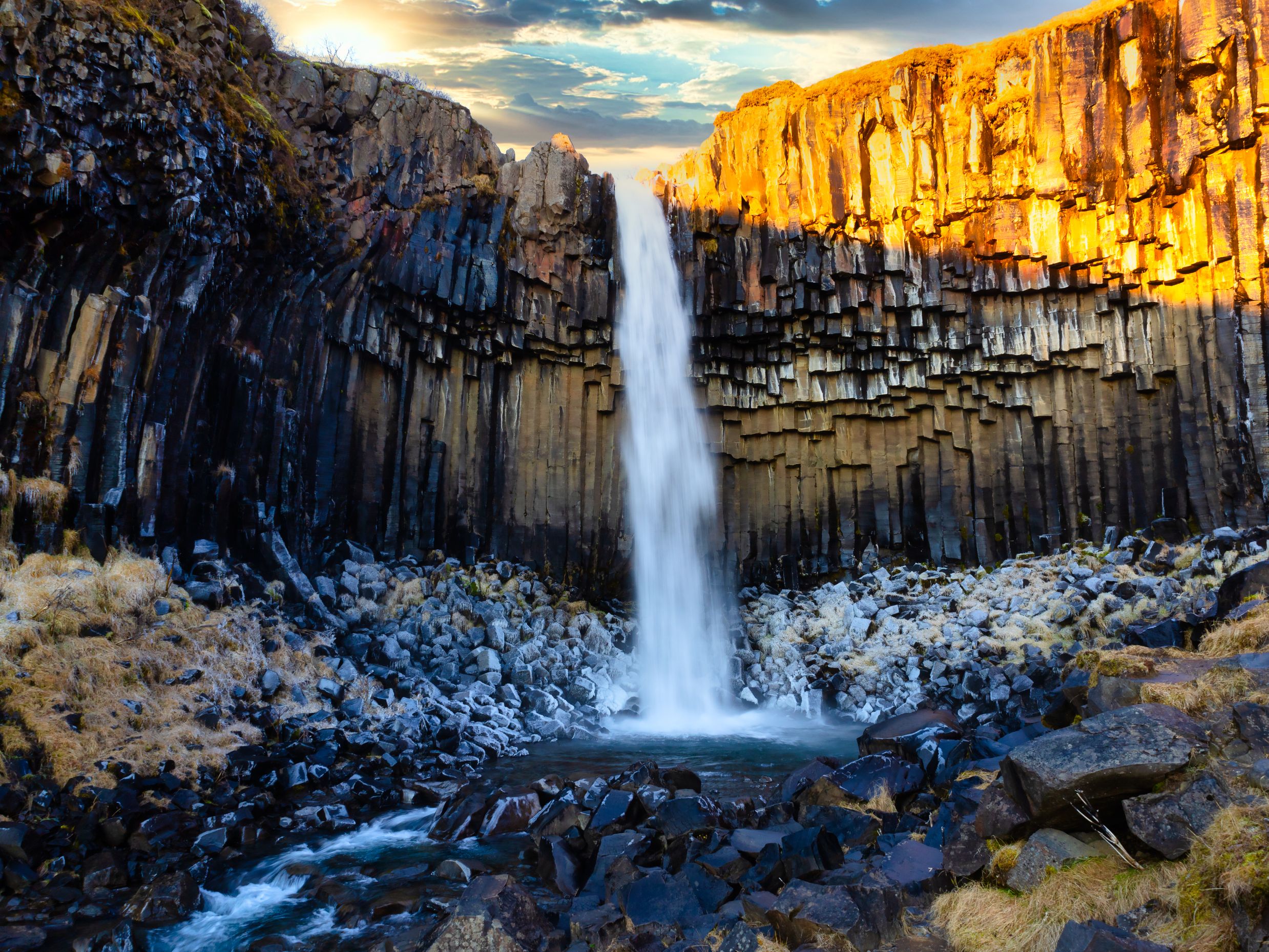 A stunning view of Svartifoss Waterfall in Iceland illuminated by bright sunlight.