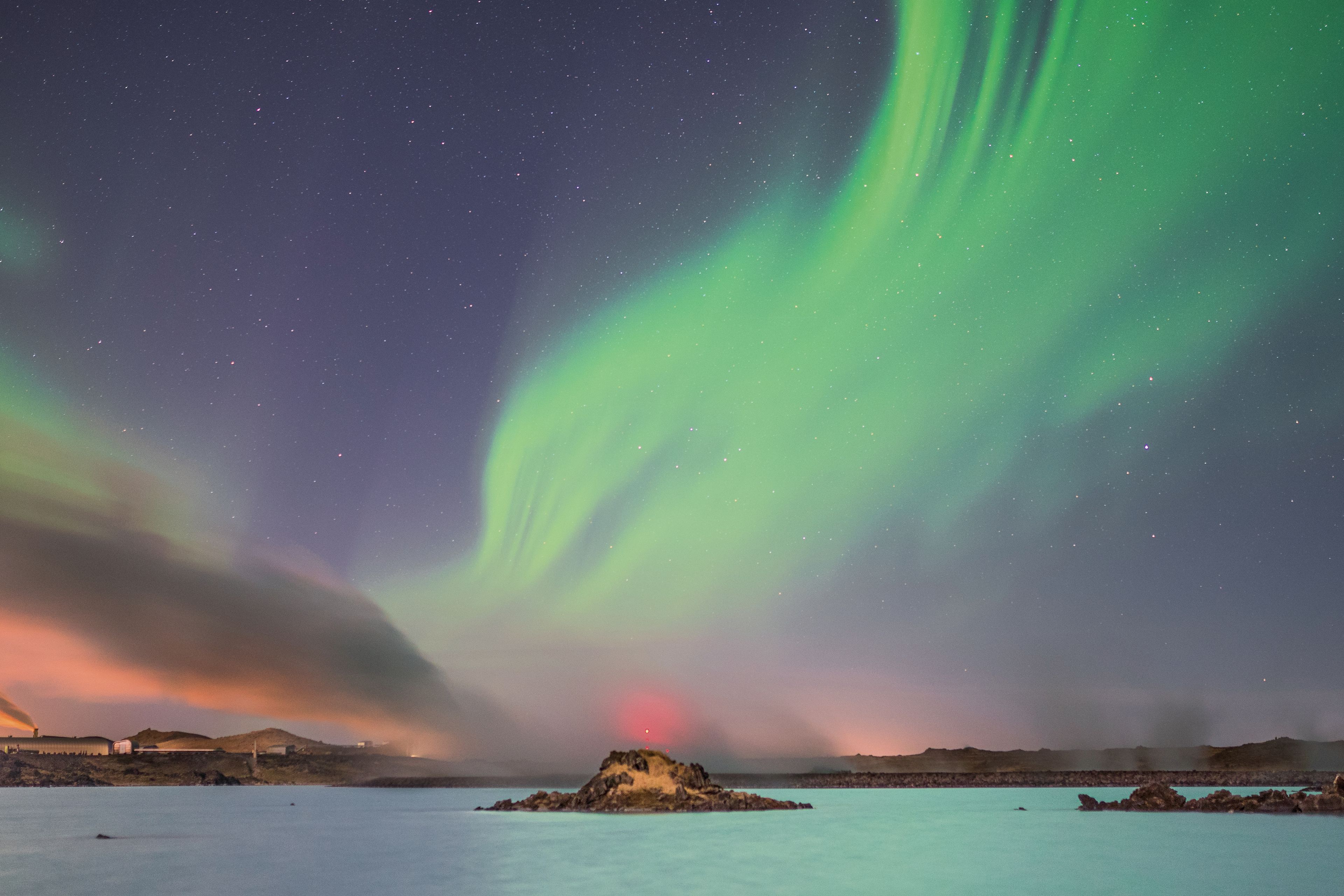 Northern lights in a pink sky during evening at Blue Lagoon, Iceland