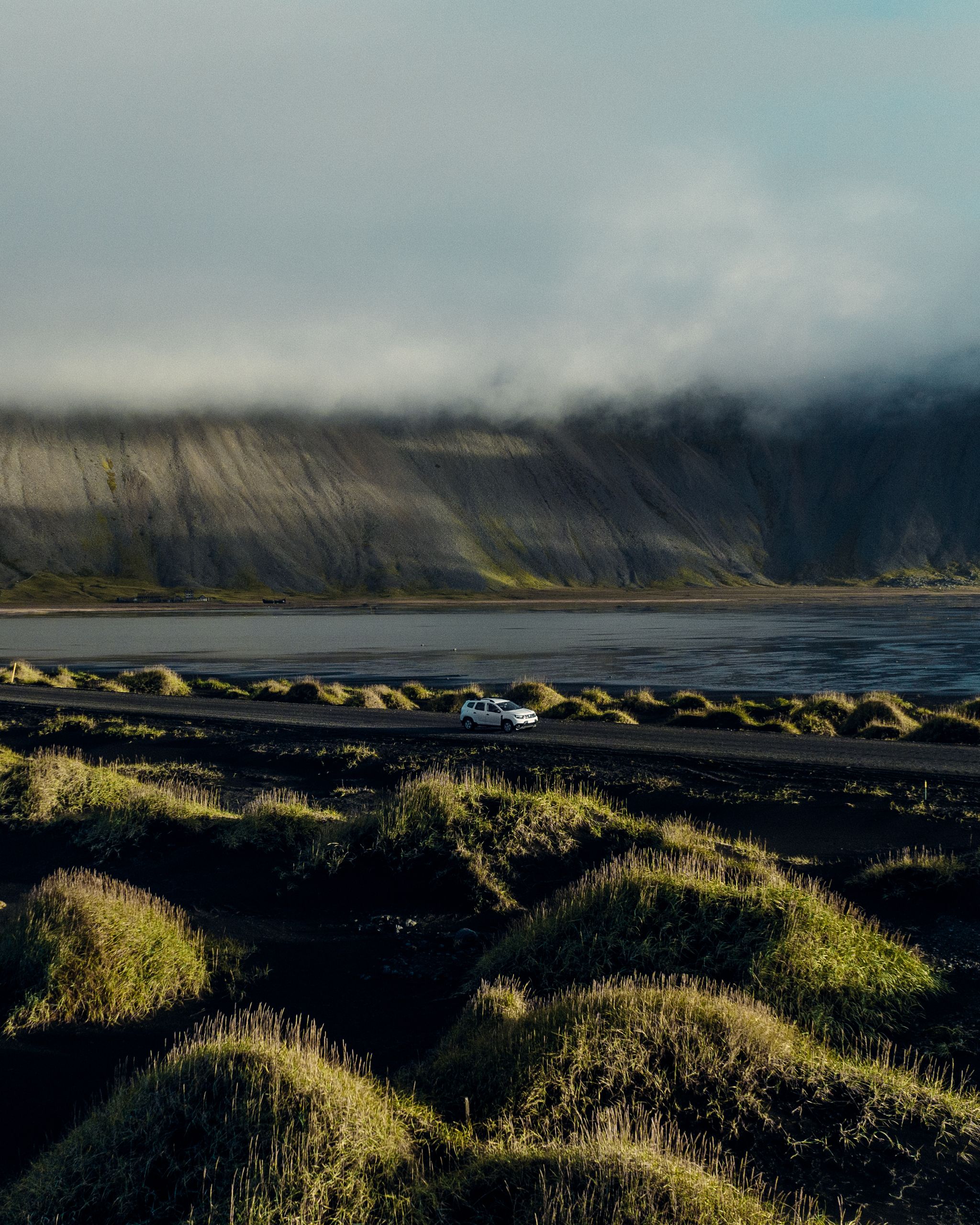 rental car on the road in Iceland in the middle of Icelandic landscapes (mountains, green plains and sea) 