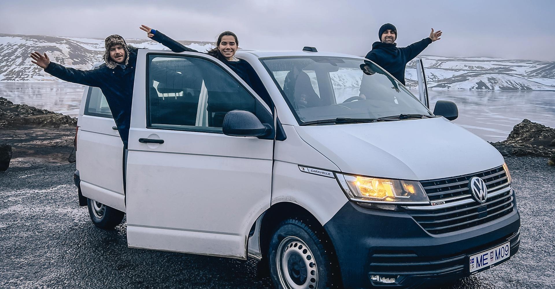 A family in a white 9 seater minivan rental car in Iceland