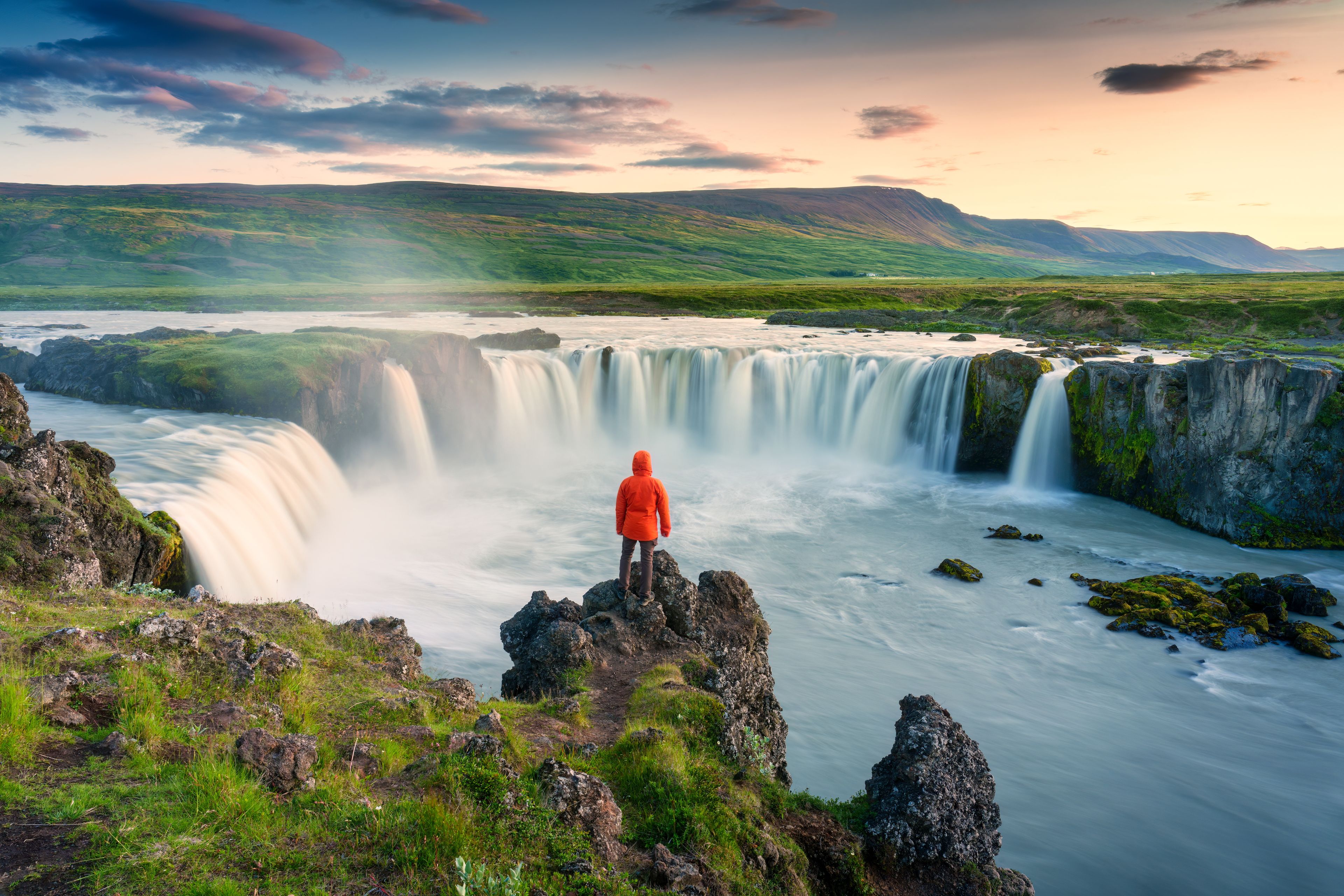 Chica con un abrigo rojo admirando Godafoss