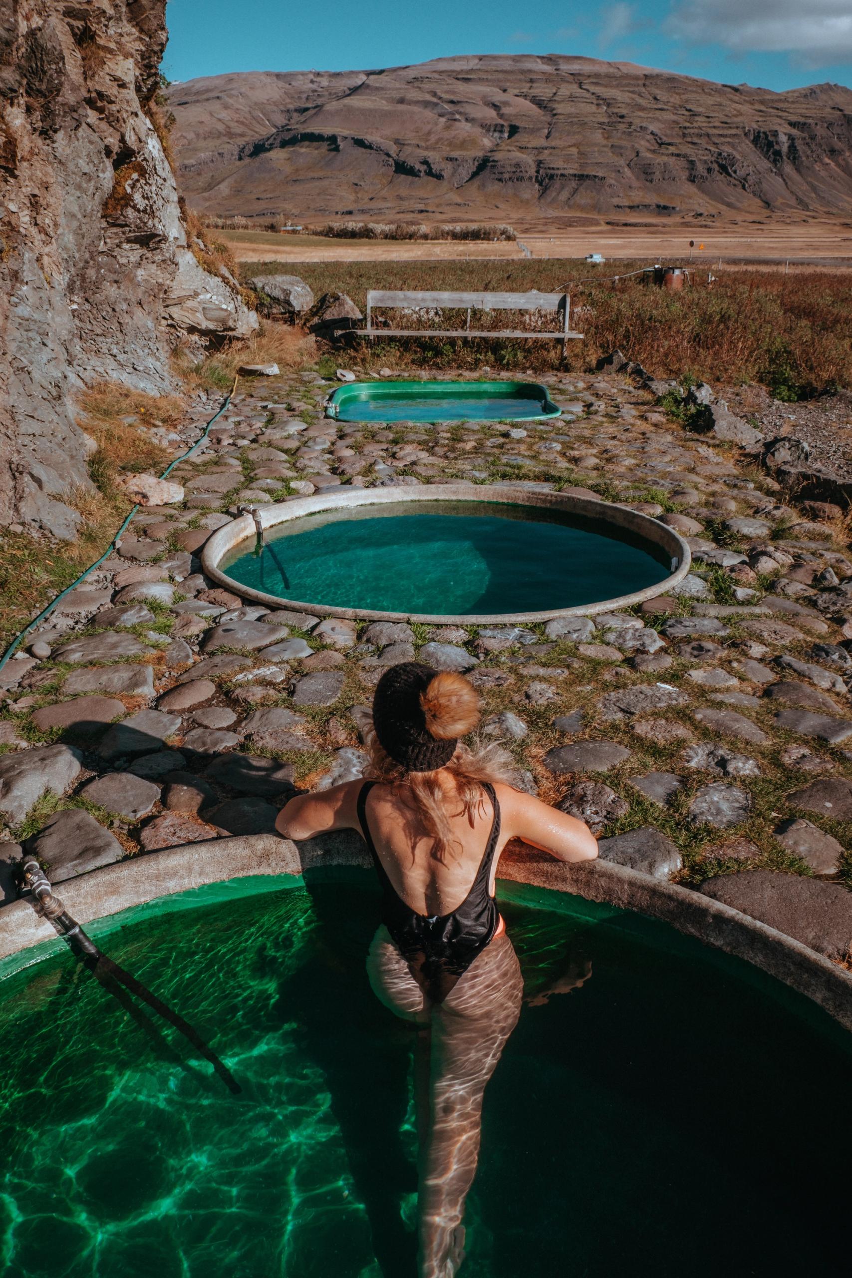 Girl relaxing in the Hoffell Hot Tubs with mountains in the background