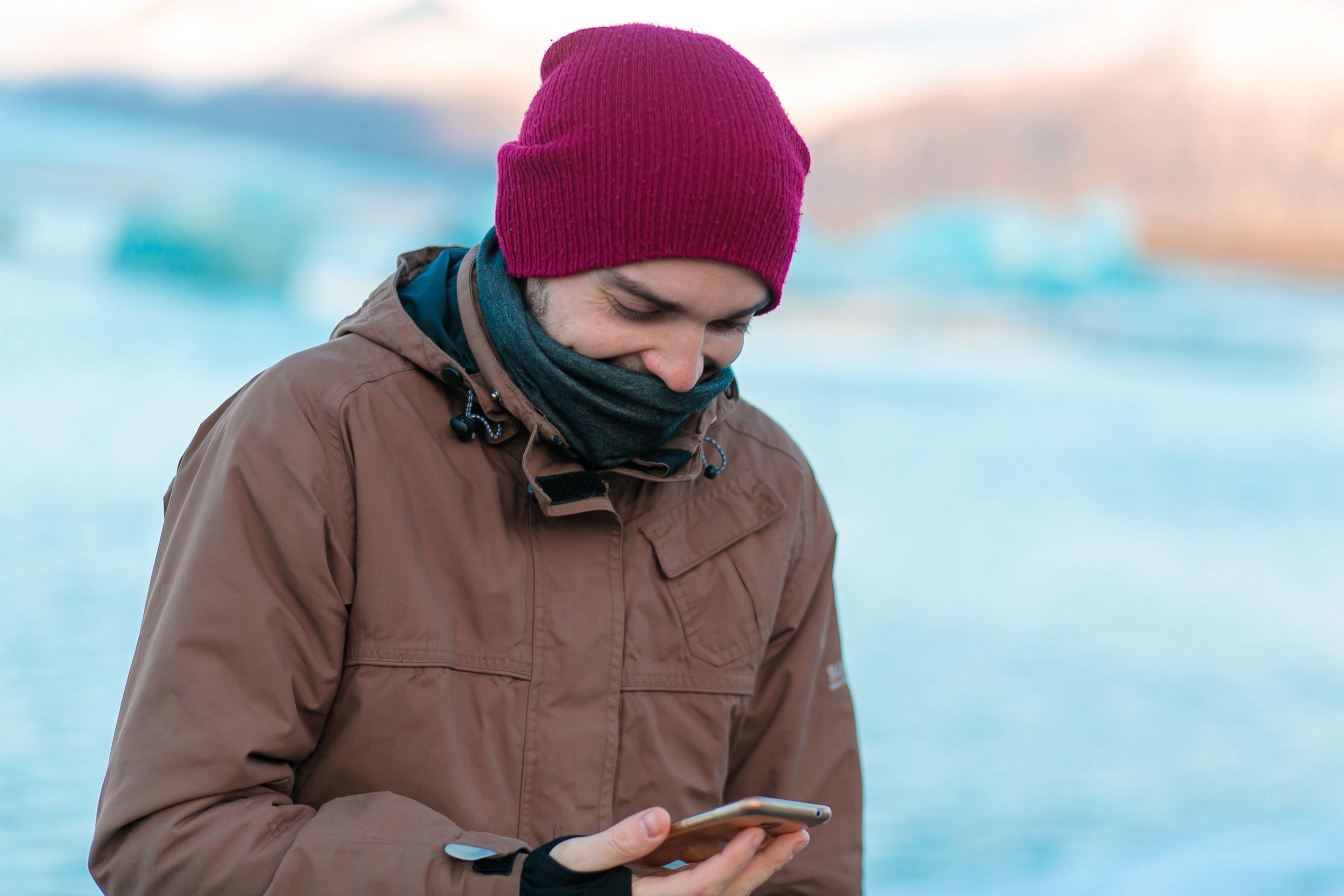 Guy-Touristenspaziergänge im Winter in Island. schaut auf sein Telefon mit geöffneter App.