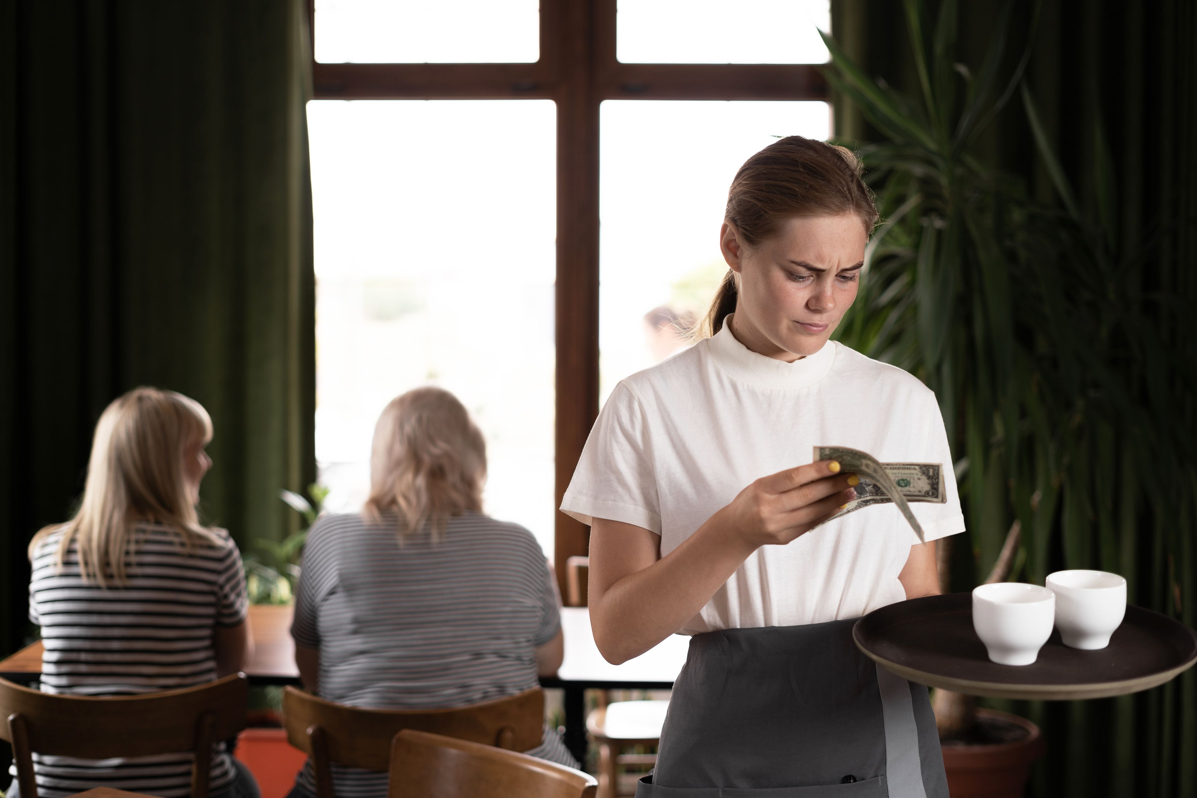 Waitress holding serving tray in restaurant with bad tips