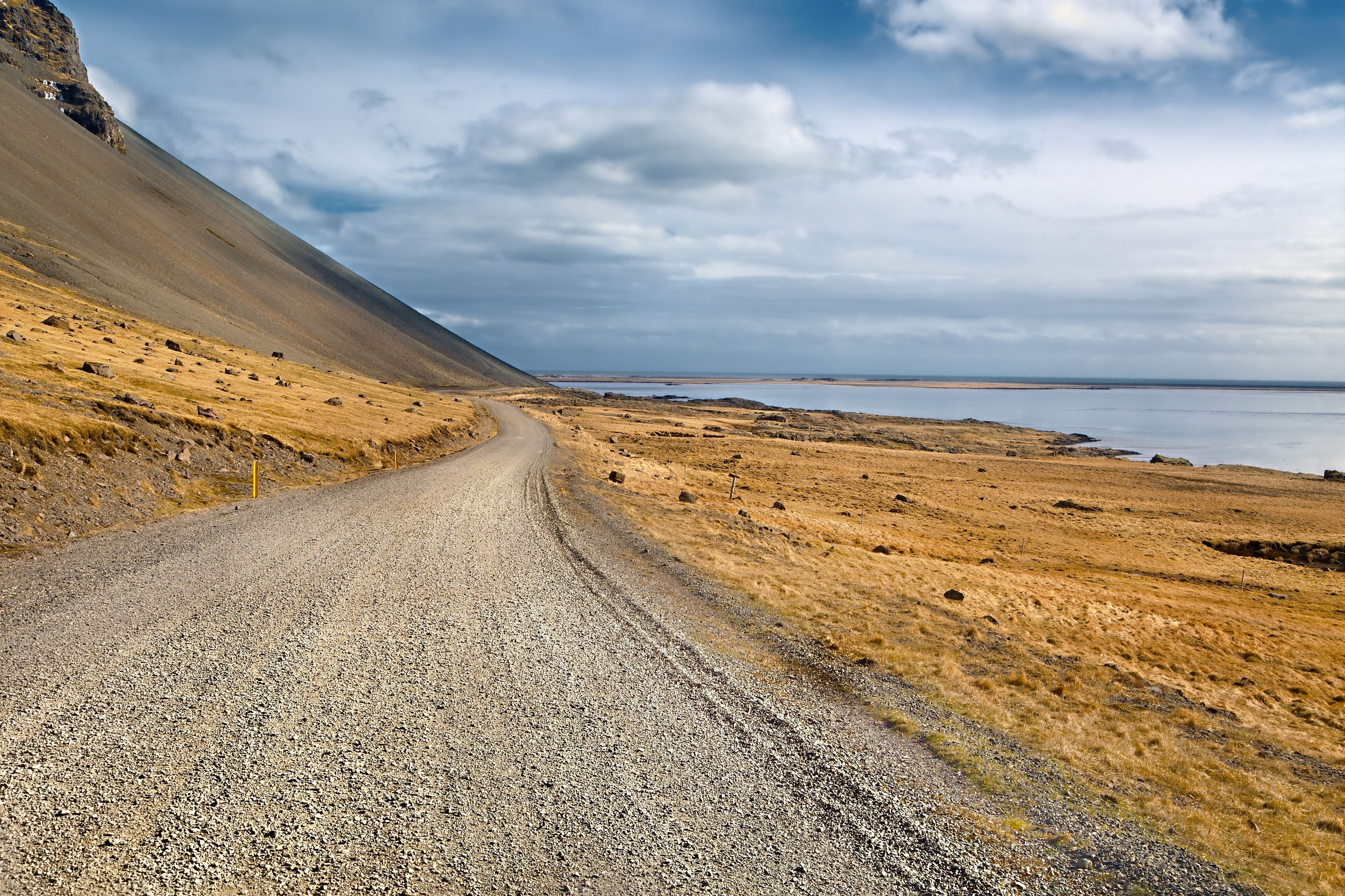 A long, winding gravel road meandering through the stark landscapes of Iceland