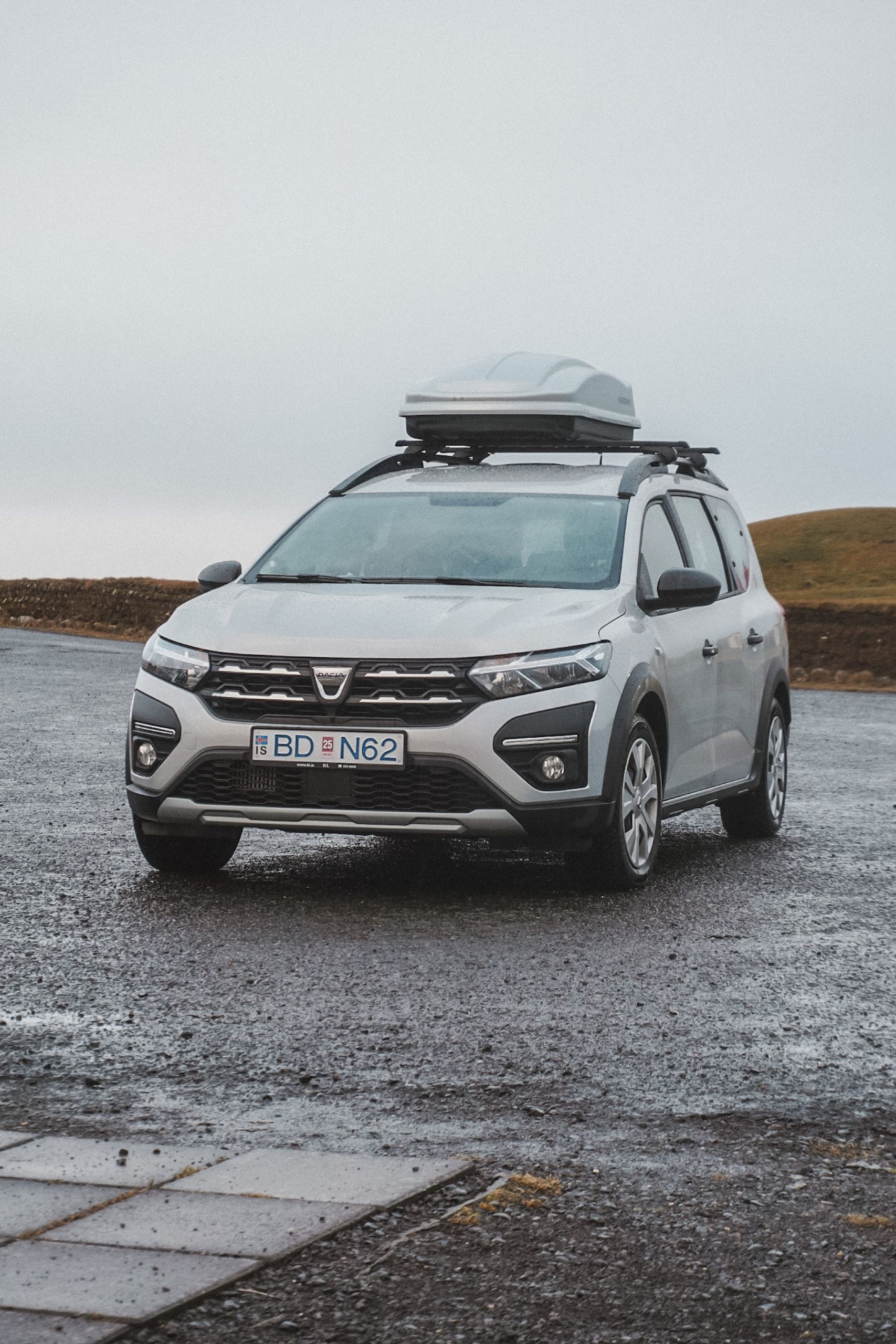 A grey Dacia Jogger parked in Iceland with a roof box 