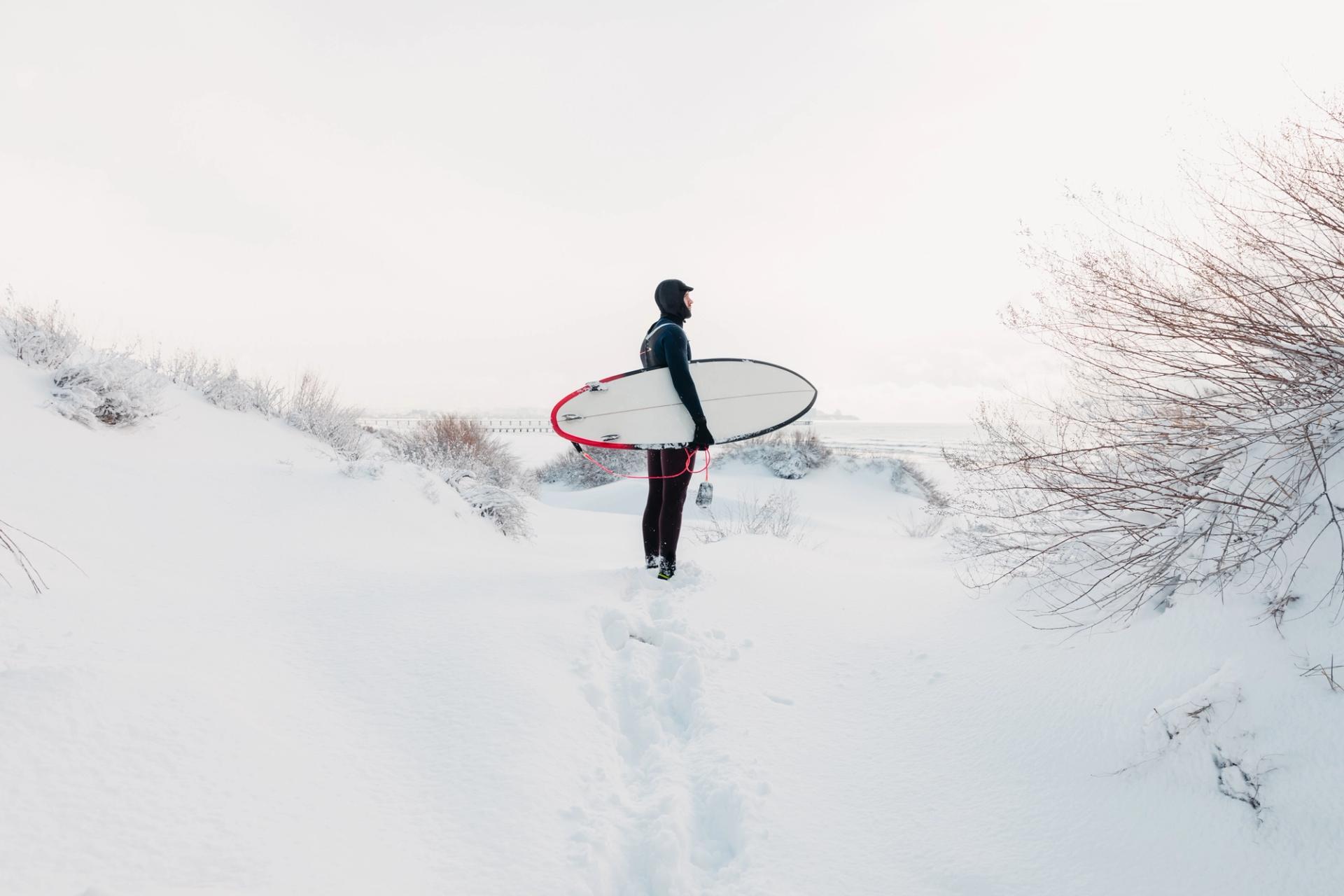 Surfer walking in the snow in iceland