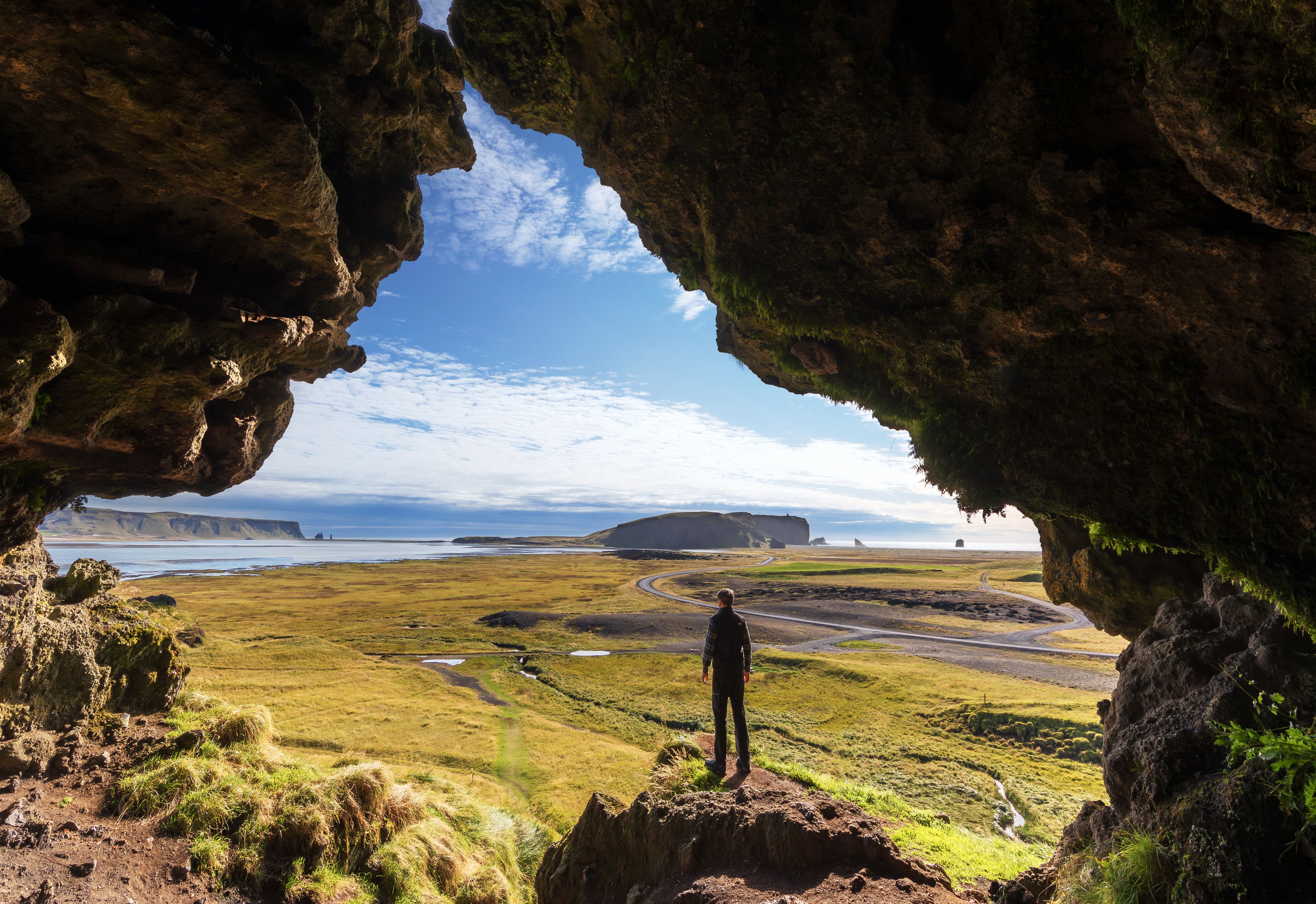 man from the Loftsalahellir Cave and view on the Black sand beach  in Iceland 