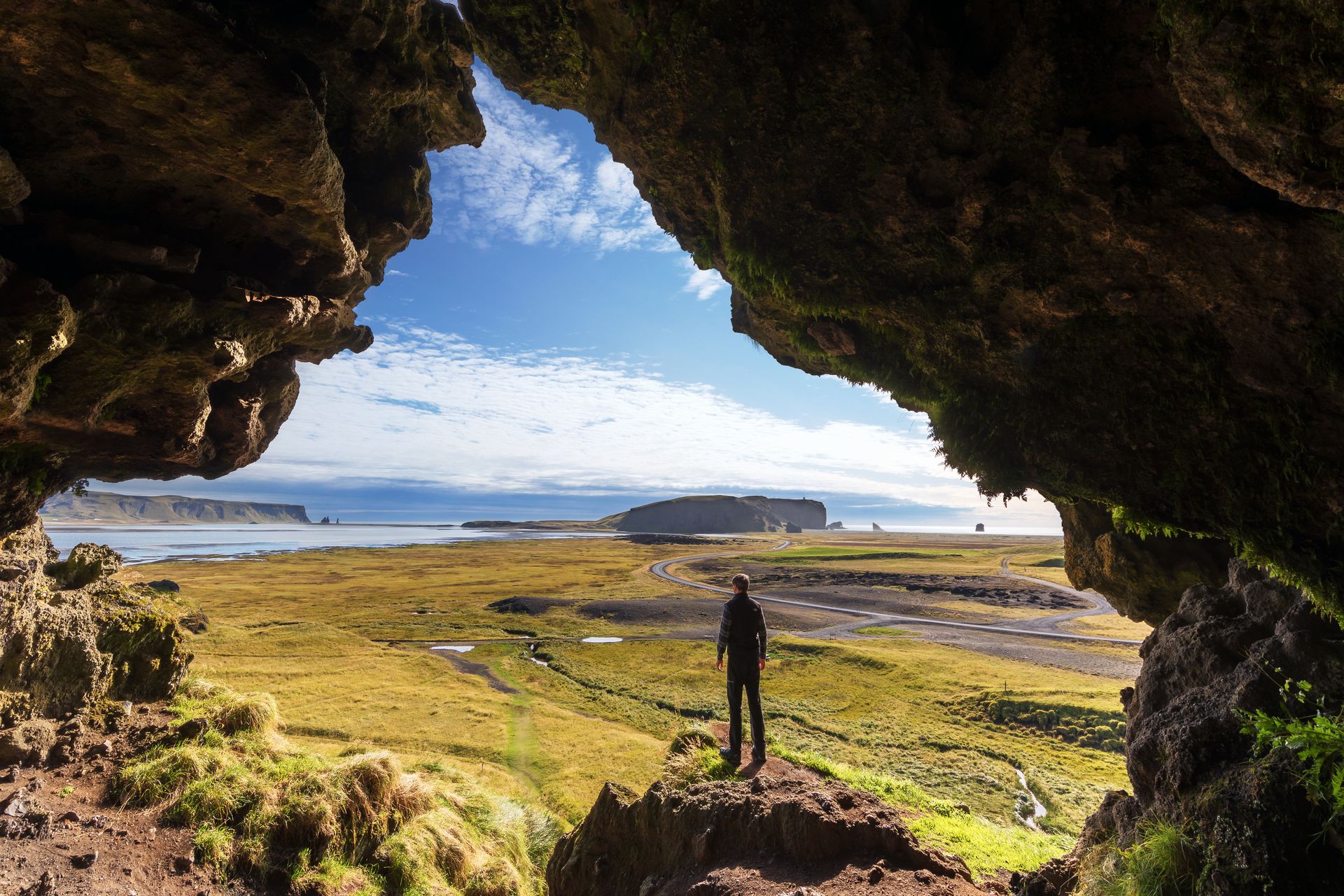 man from the Loftsalahellir Cave and view on the Black sand beach  in Iceland 