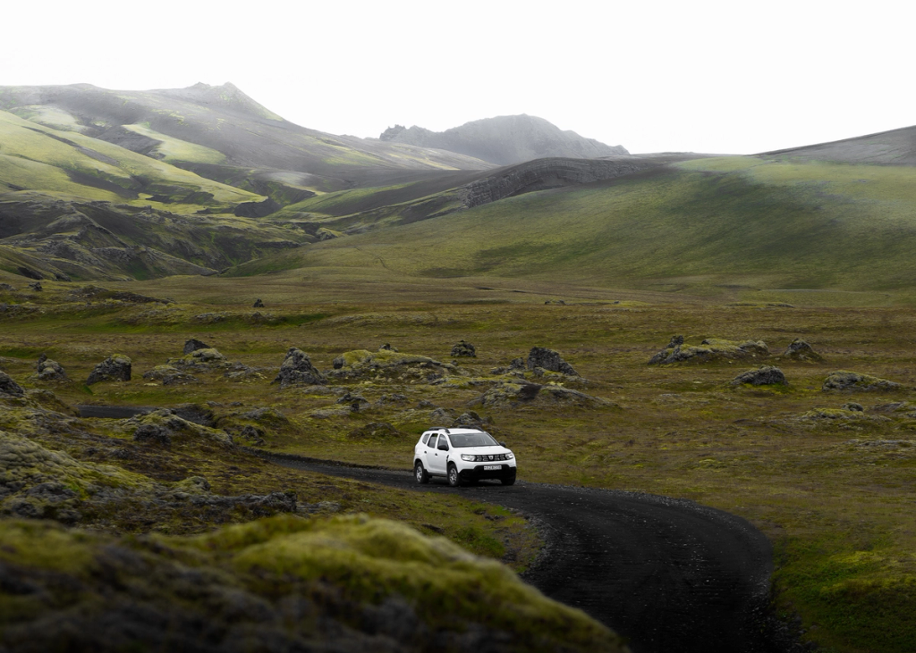 Dacia Duster driving on a gravel road in Iceland near green grass and moss