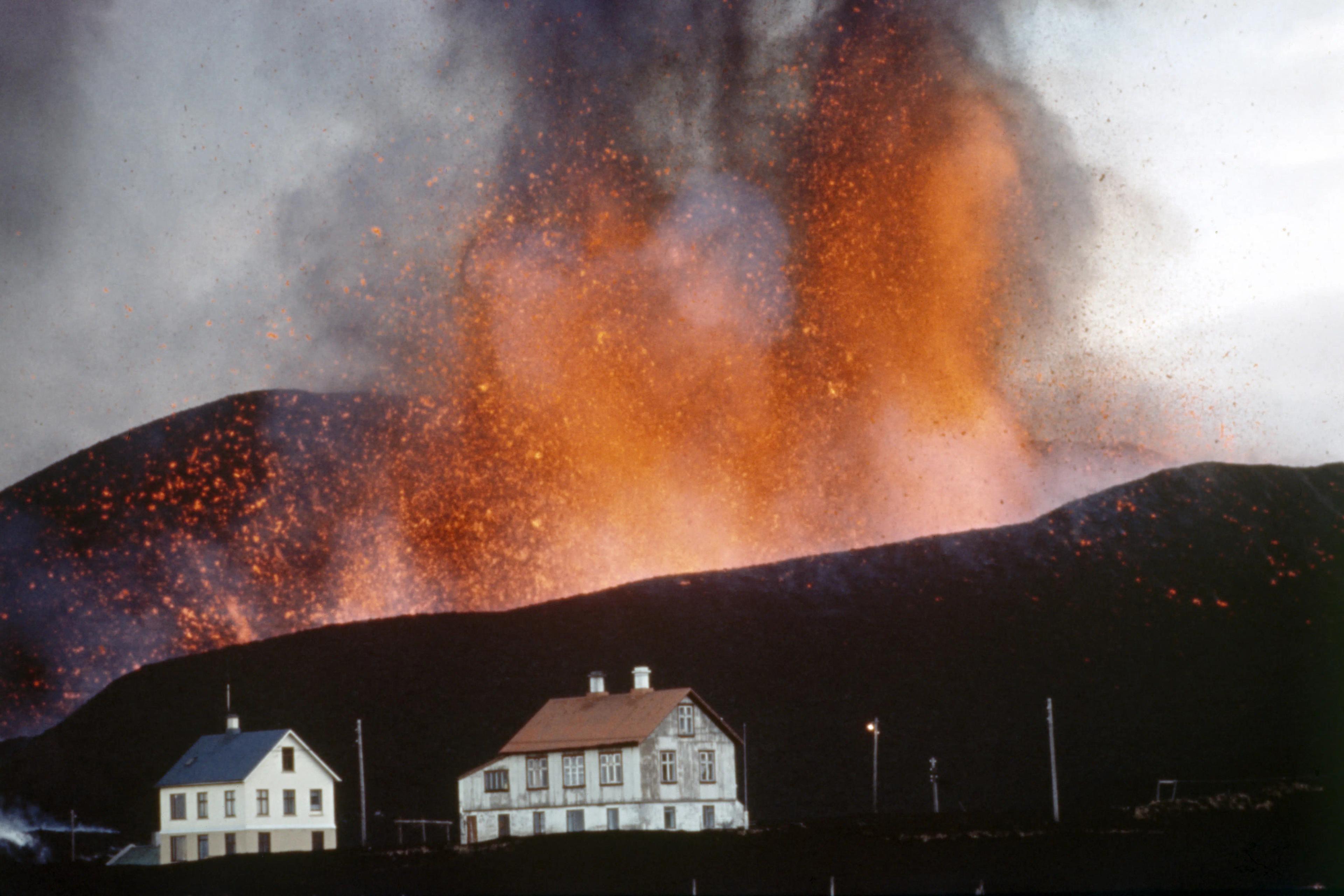 A view of Eldfell volcano with eruption in the background