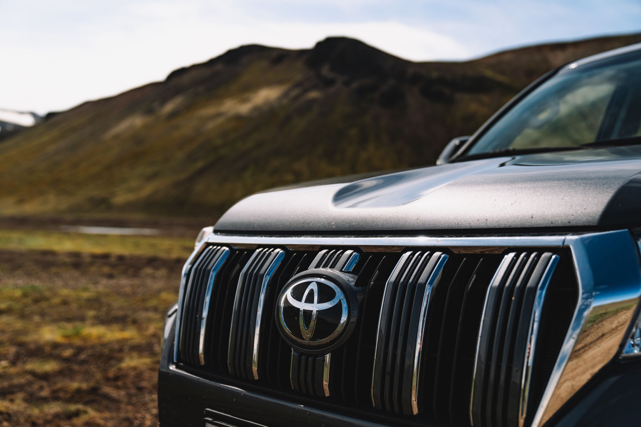 丰田标志在冰岛壮丽崎岖地貌的背景下，于Go Car Rental的租赁车上醒目展示。