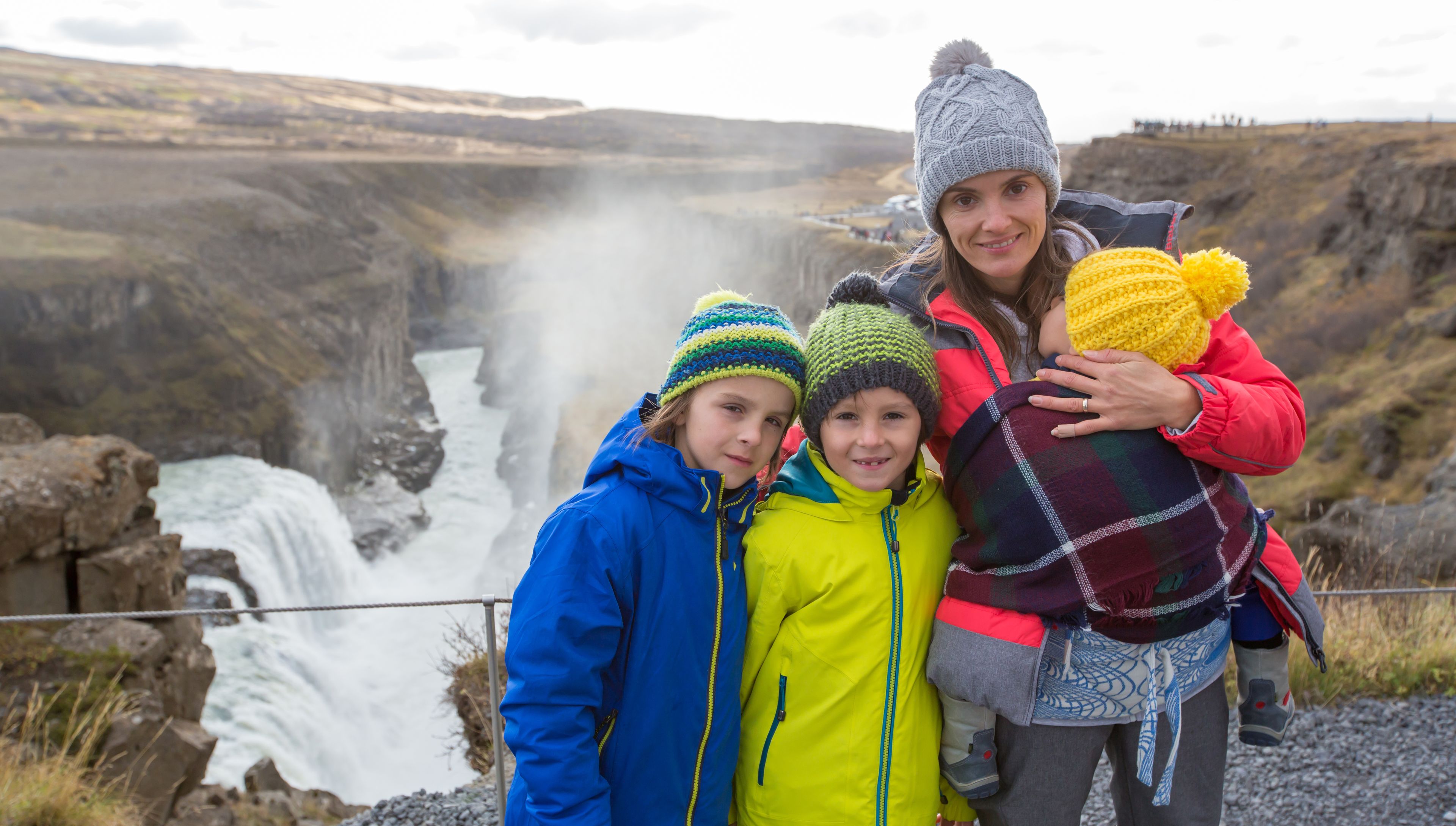 mother with her 3 children, come to discover Iceland in winter, there is in the background one of the numerous waterfalls of Iceland 