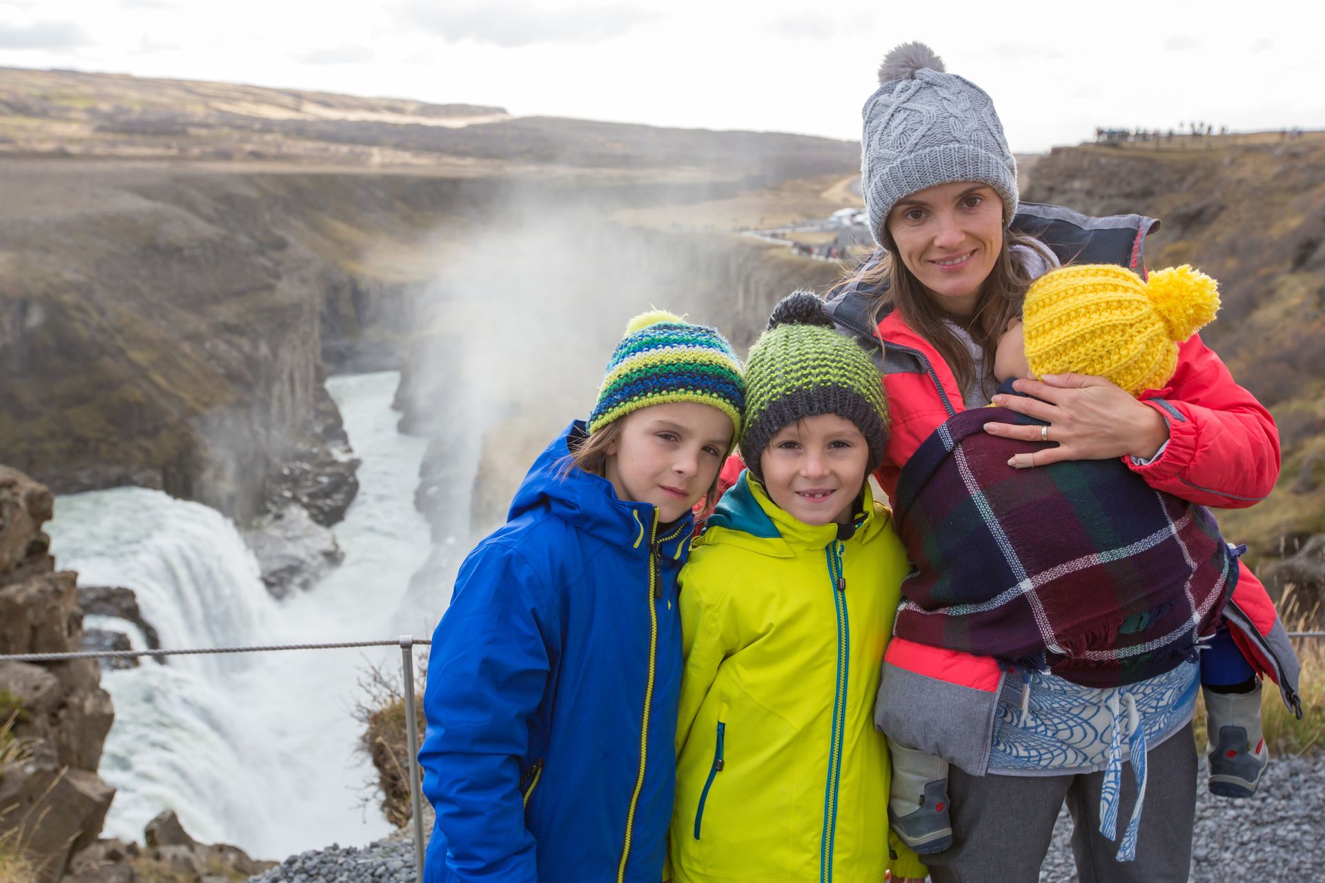 mother with her 3 children, come to discover Iceland in winter, there is in the background one of the numerous waterfalls of Iceland 