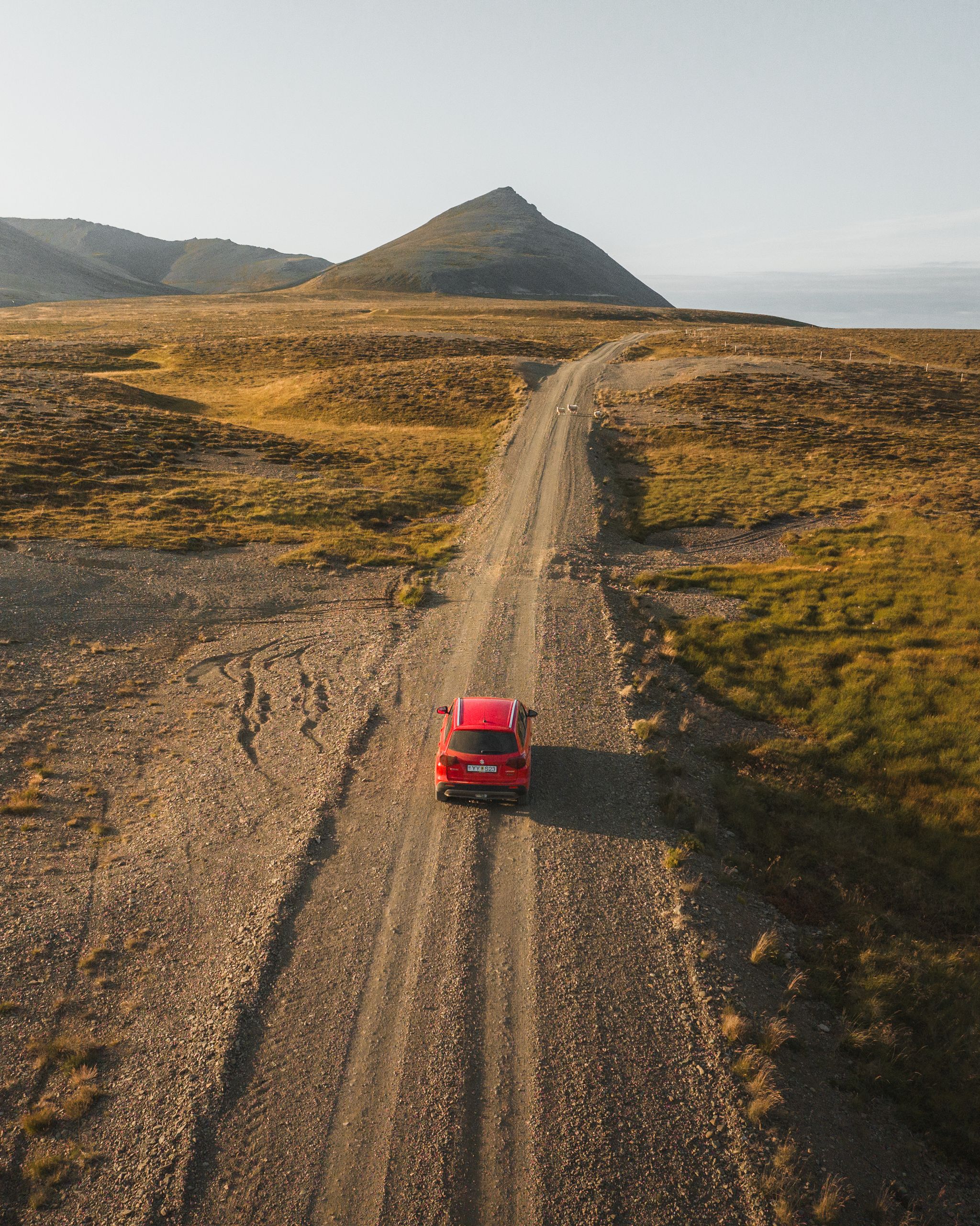 4x4 Suzuki Vitara rouge en location conduisant loin de la caméra en Islande