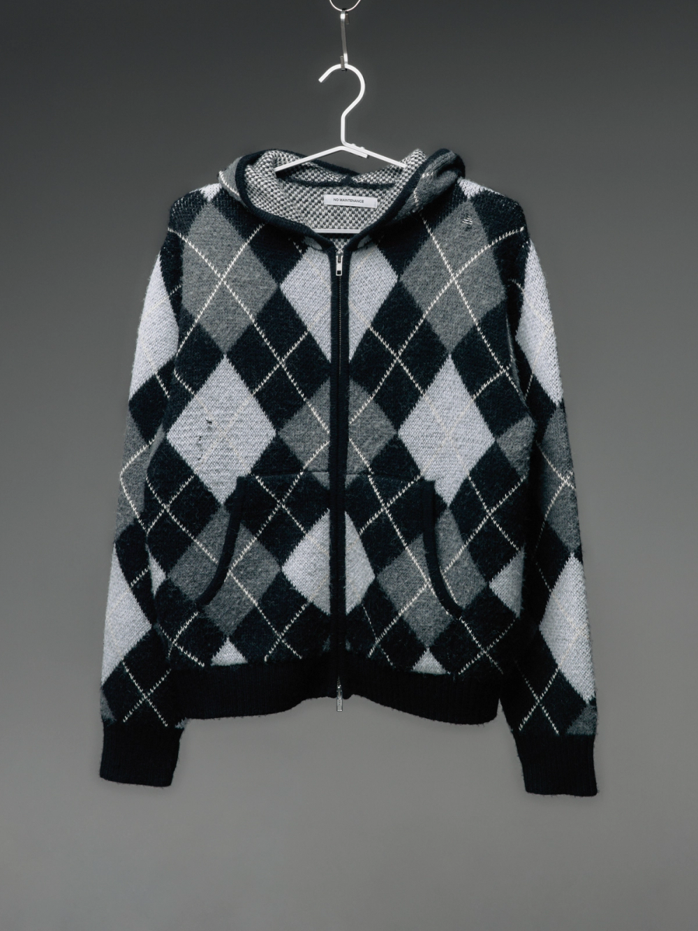 Monochromatic argyle zip-up hoodie hanging on a hanger.